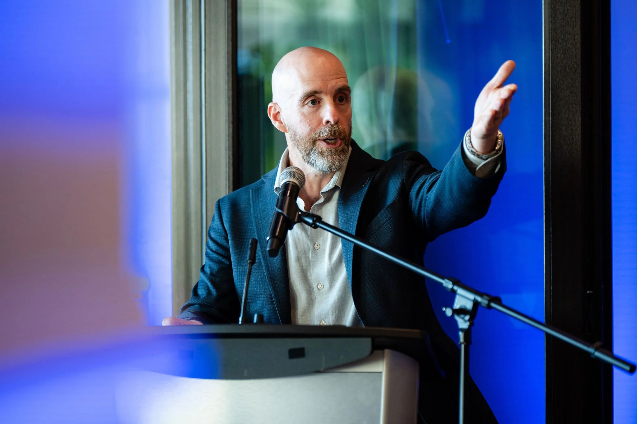Business speaker addressing guests from a blue-lit podium