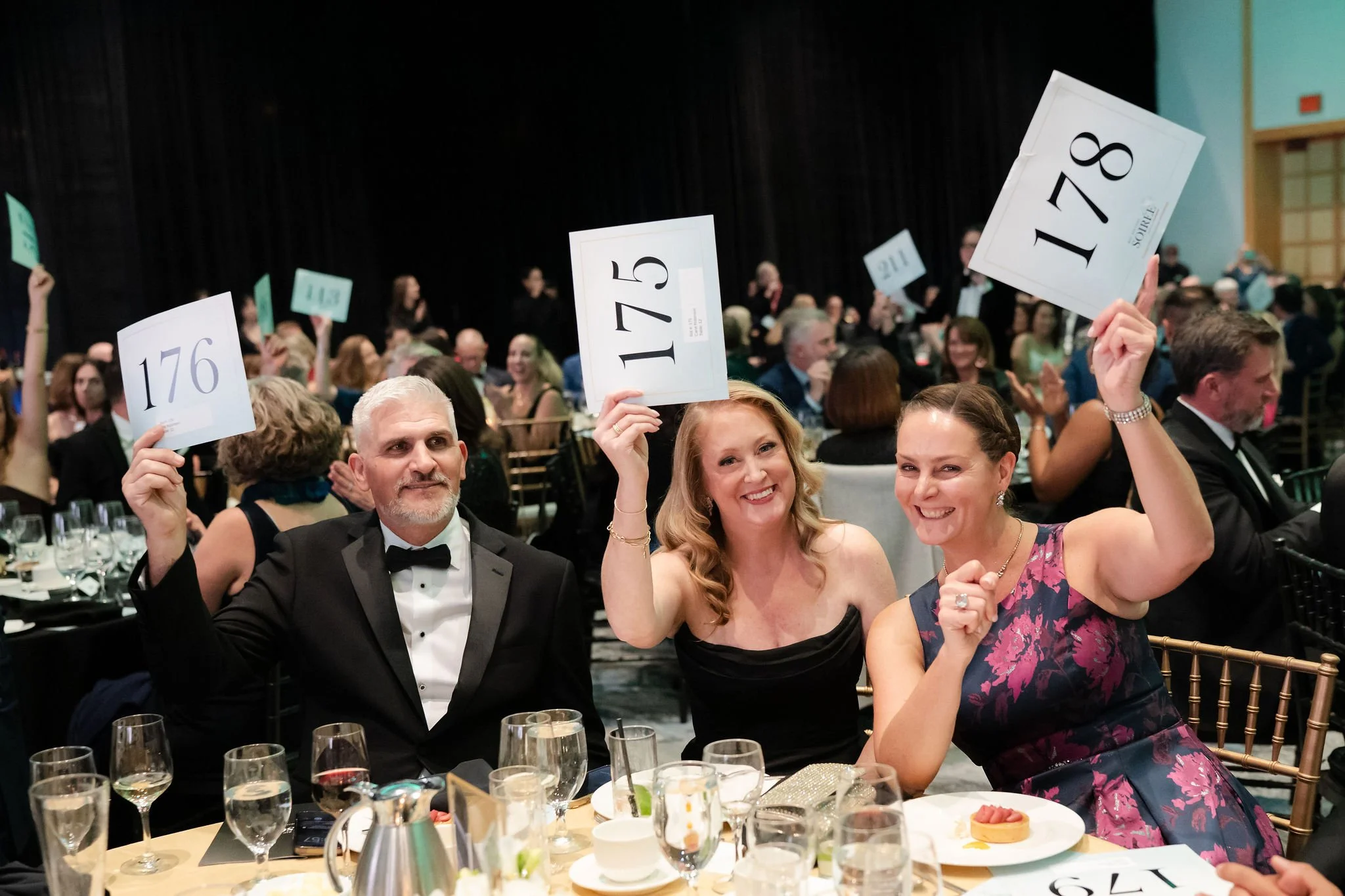 Gala guests raising numbered paddles during a fundraising auction