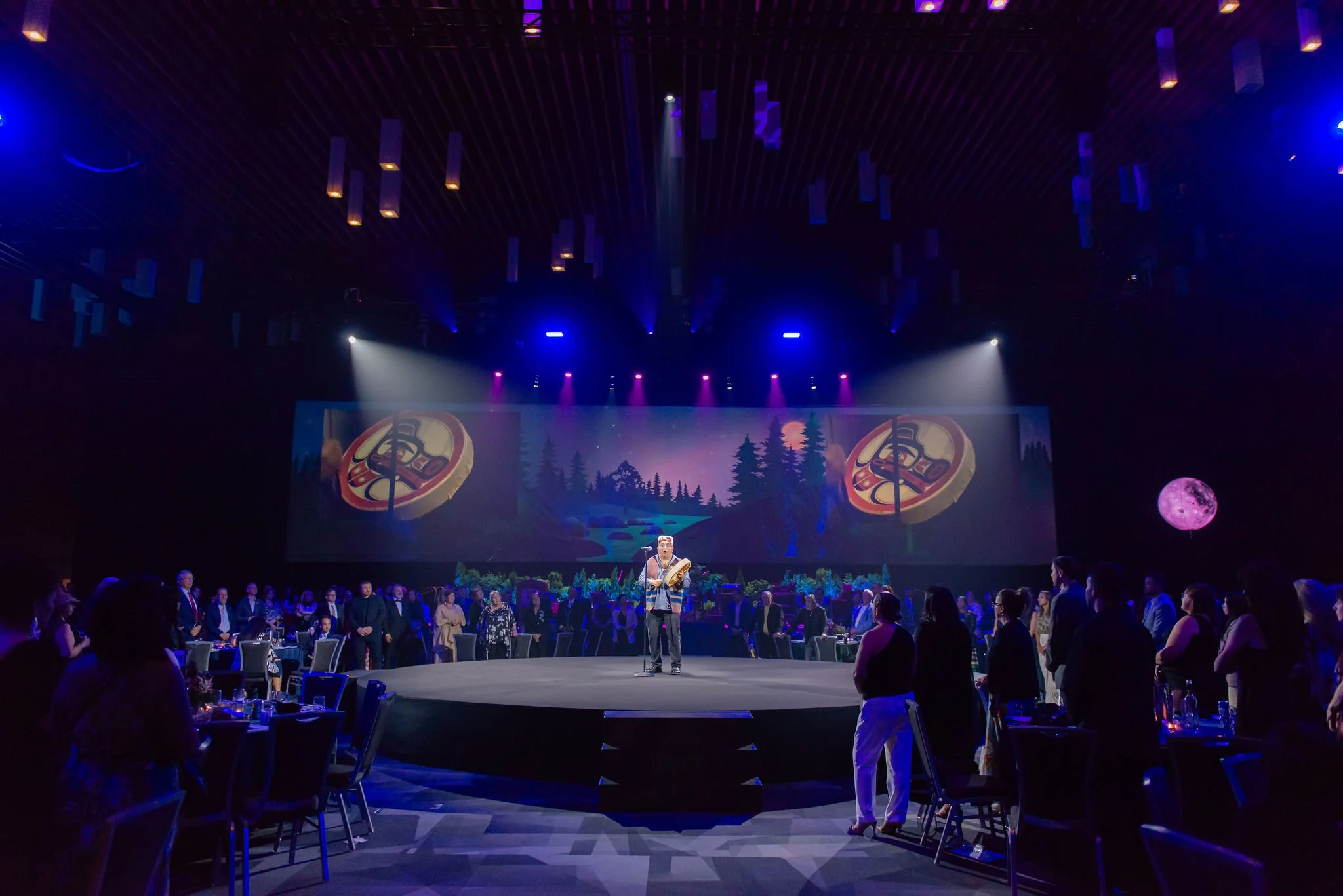Performer on a circular stage during a large-scale evening event