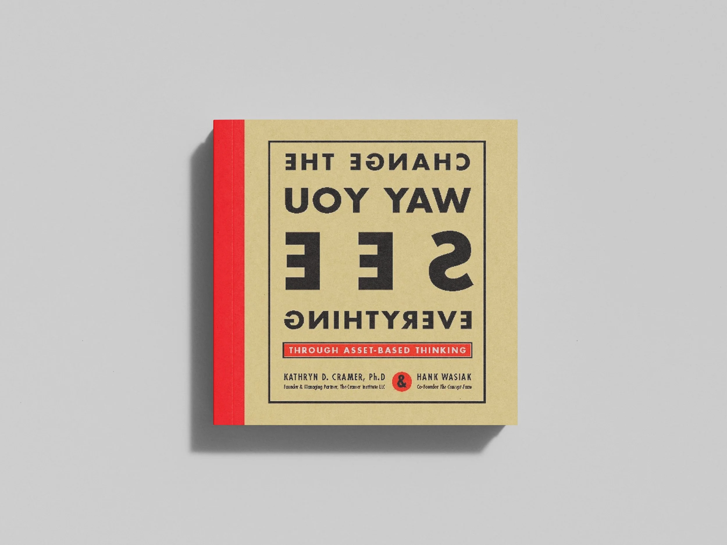 A book titled "Change the Way You See Everything" by Kathryn D. Cramer, Ph.D., and Hank Wasiak, with a red spine, placed on a light gray surface.