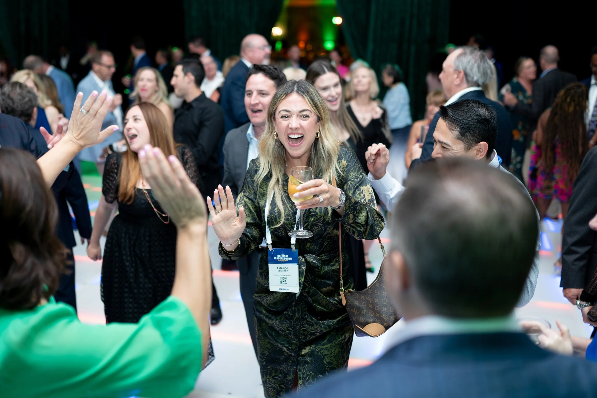 A group of people dancing and celebrating at a social event or party, with a woman in the center holding a drink, smiling, and enjoying the moment.