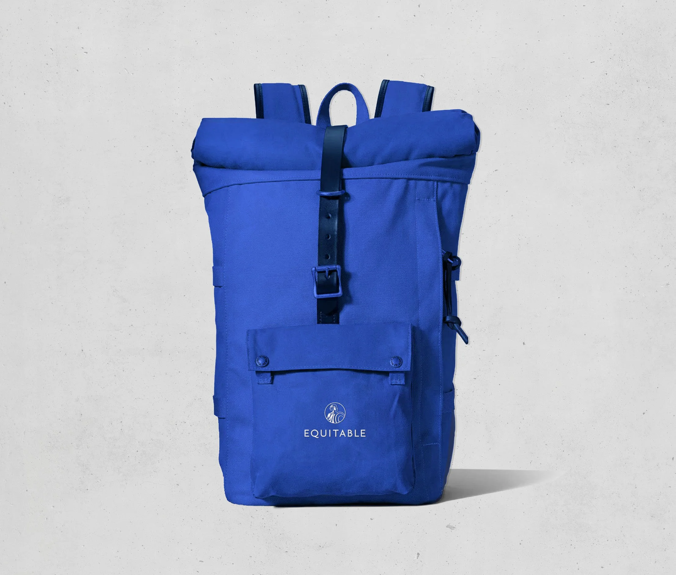 Blue backpack with a front pocket and logo that reads 'EQUITABLE' on a plain background.