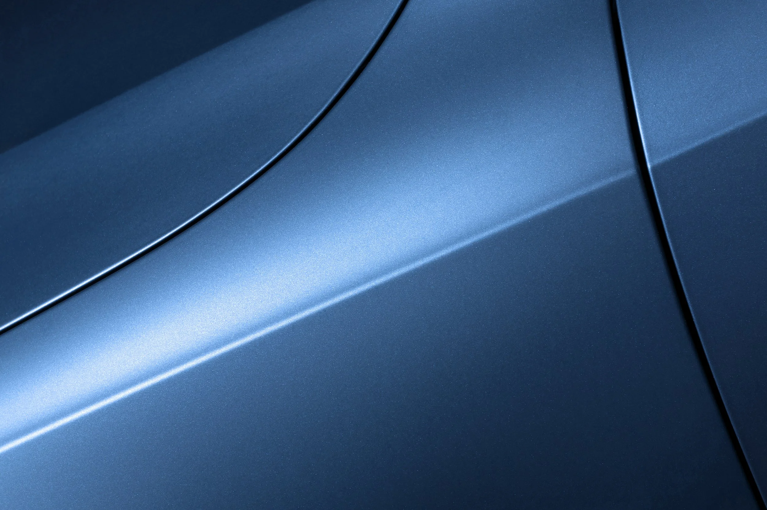Close-up of a blue metallic car surface with smooth curves and gloss finish.