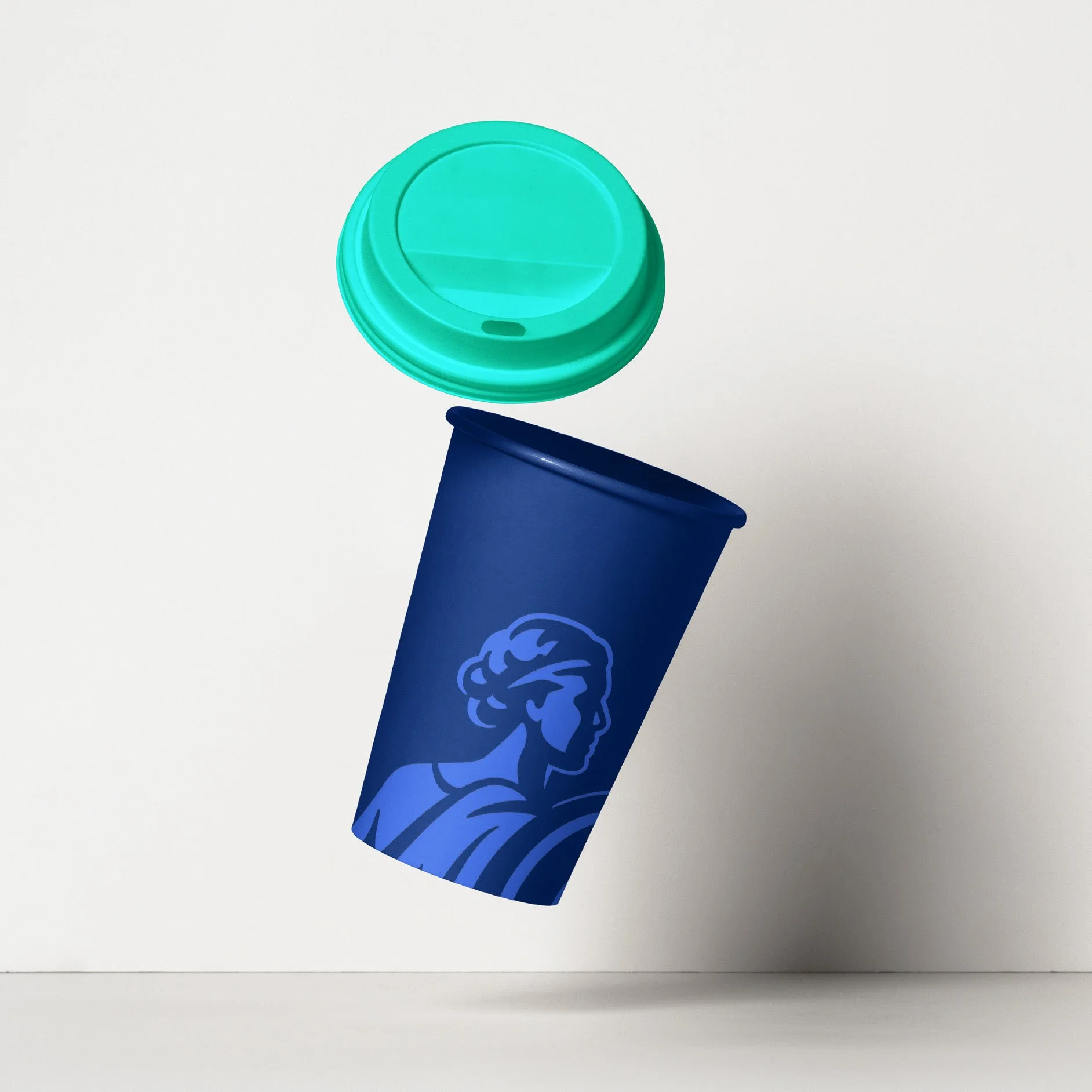 A blue to-go coffee cup with a logo of a woman’s profile, floating above a white surface, with a teal-colored plastic lid positioned above the cup and appearing to be falling.
