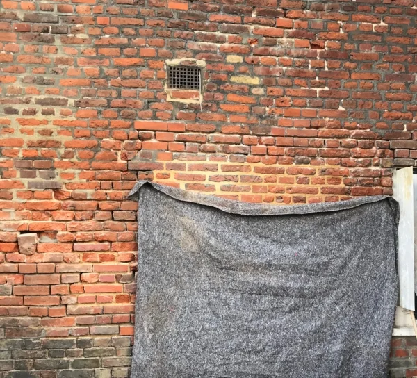 The area above the grey blanket shows experimenting with treatments with the new lime mortar. Areas where bricks will have to be replaced are also clear.
