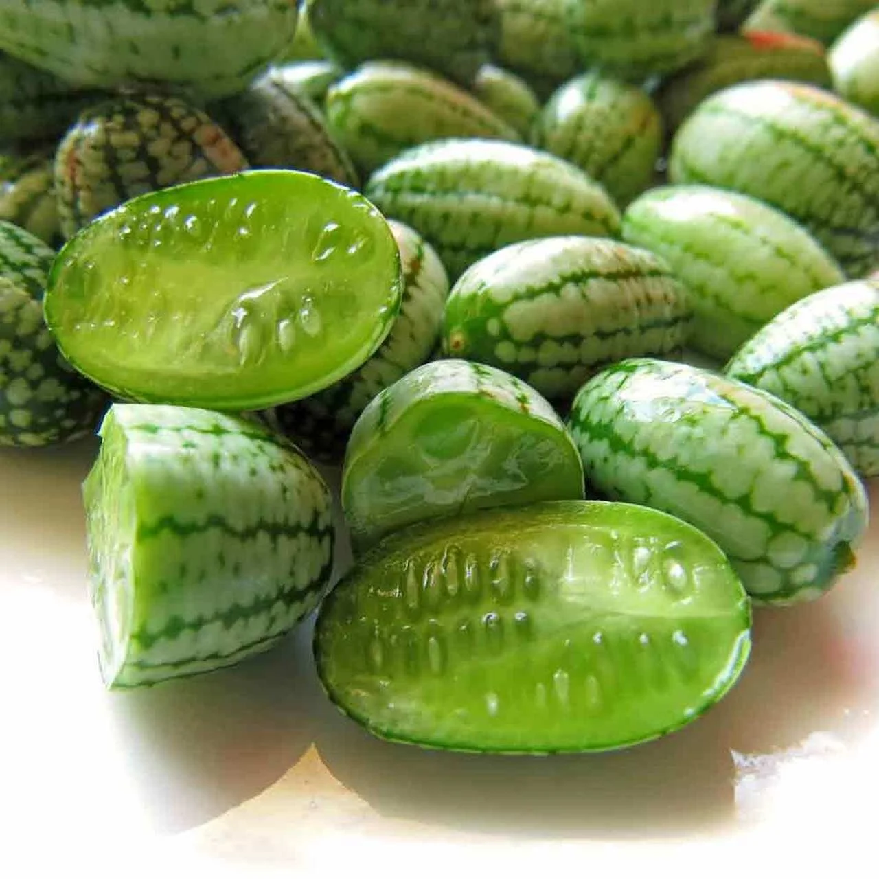 Cucamelons sliced to open showing the cucumber-like interior and melon-like exterior