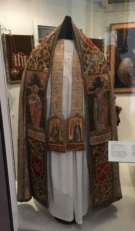 The cope in Fulham Palace’s older display with the stole visible.©️ TripAdvisor, user Tp19862011 (April, 2015) https://media-cdn.tripadvisor.com/media/photo-s/07/af/6d/0a/fulham-palace-museum.jpg
