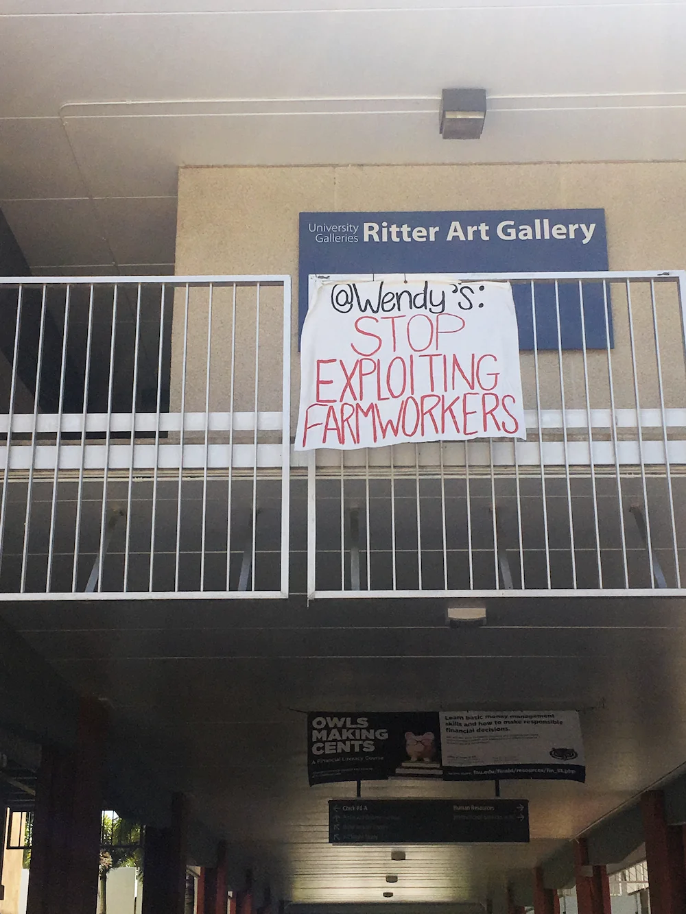 After passing a unanimous resolution to ban Wendy’s from campus until the fast-food giant joins the Fair Food Program, students at Florida Atlantic University in Boca Raton, FL, suspend a banner from the second floor balcony at the Ritter Art Gallery.