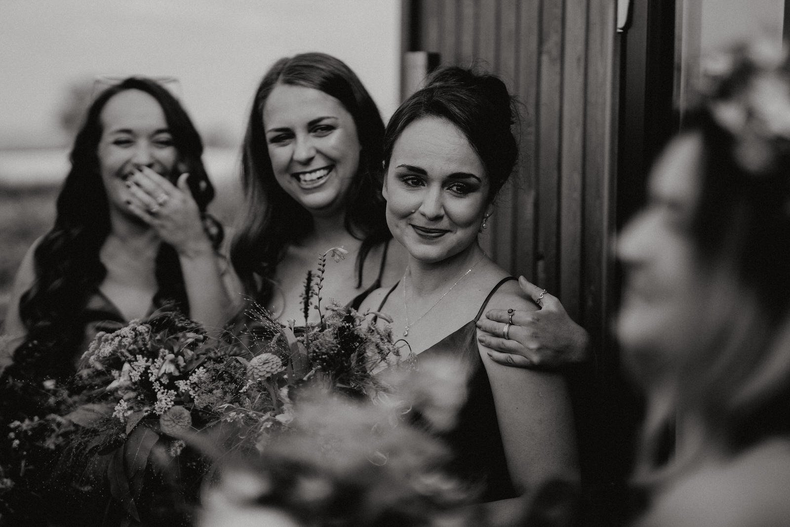 Bridesmaids look on at bride in black and white