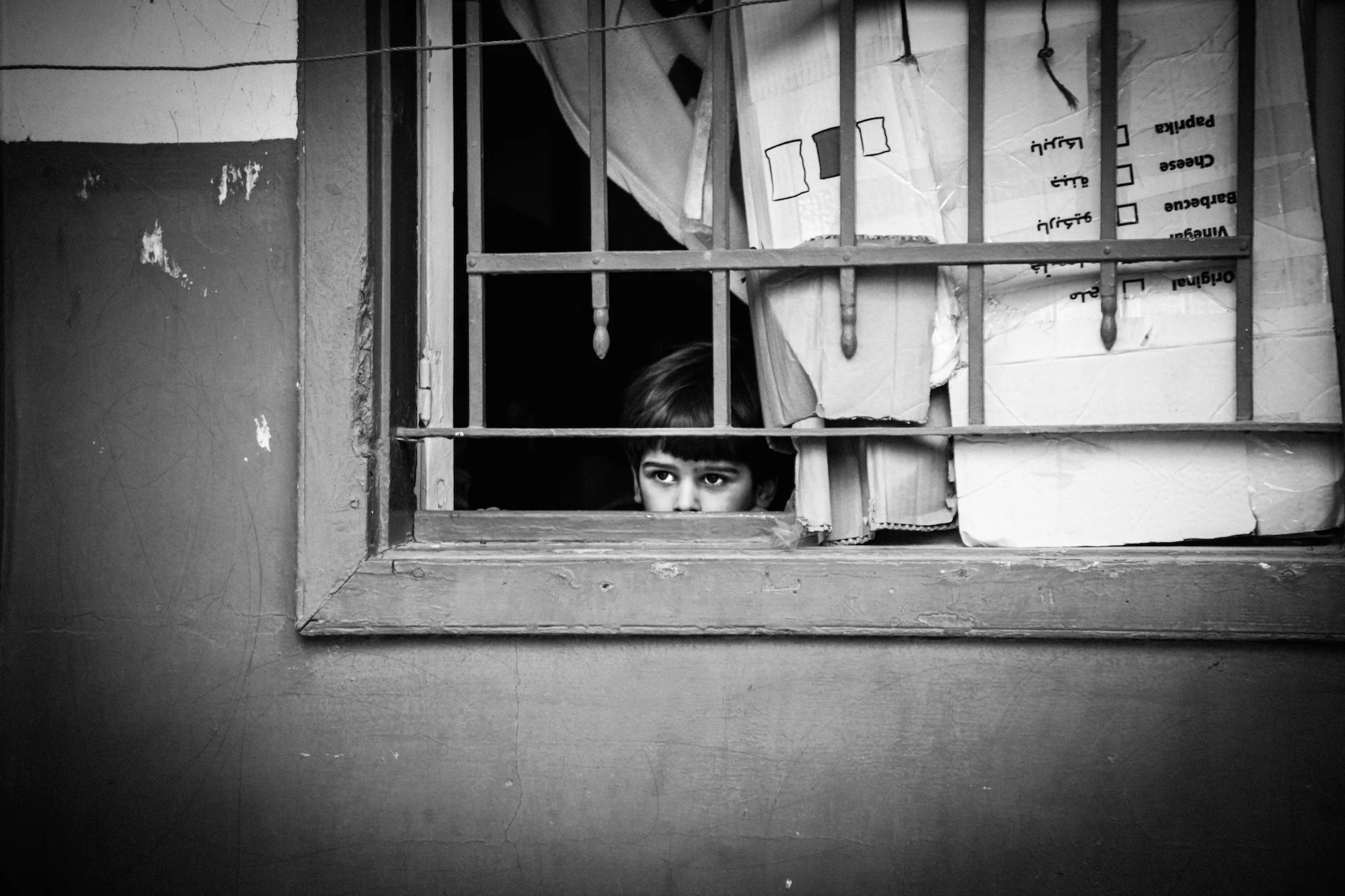 A young Syrian child peers out of a window in Lebanon's Beka'a Valley. Christina Malkoun/IRIN