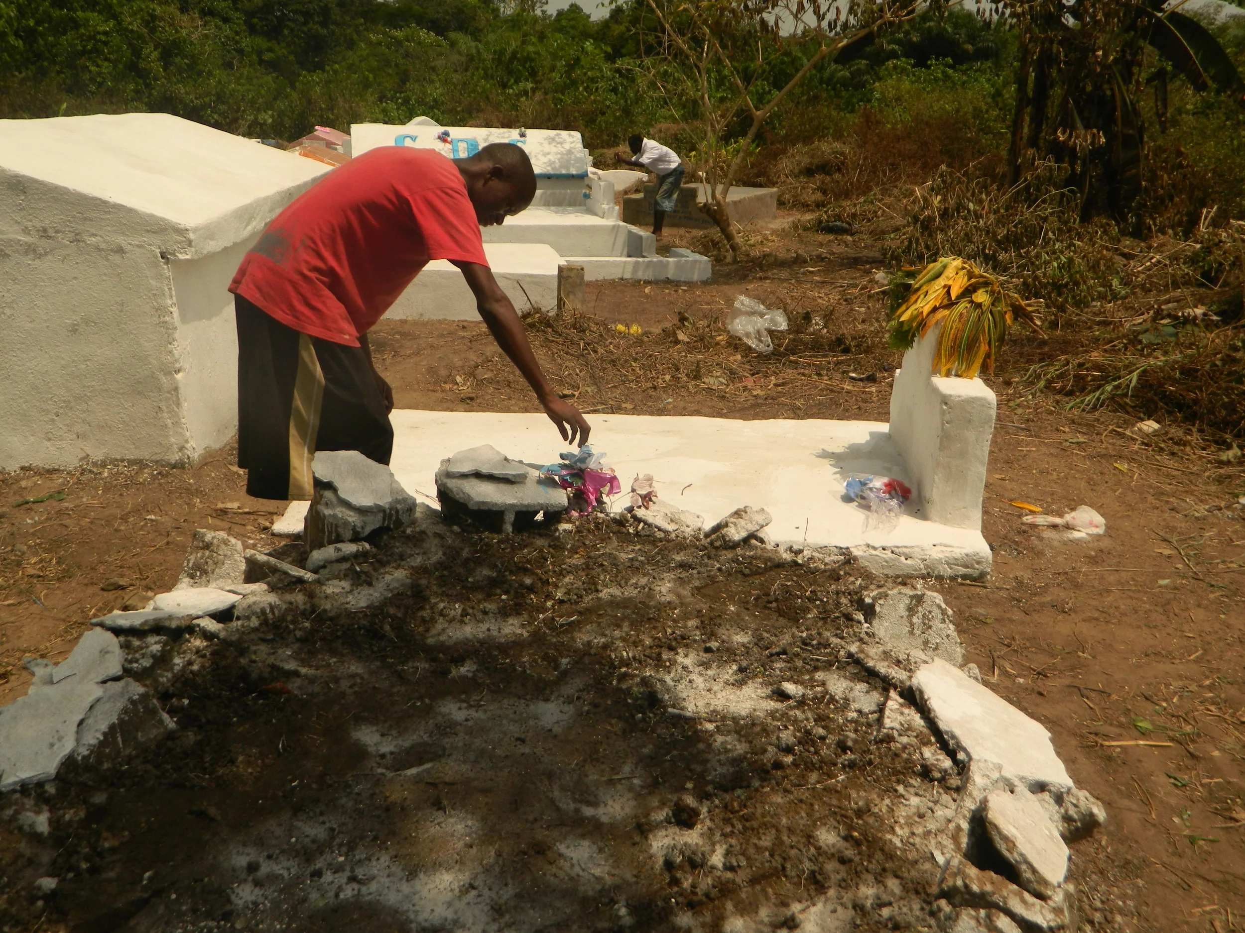Bettar Howard tends to the grave of his mother in Unification Cemetery in Monrovia on 11 March. (Prince Collins/IRIN)