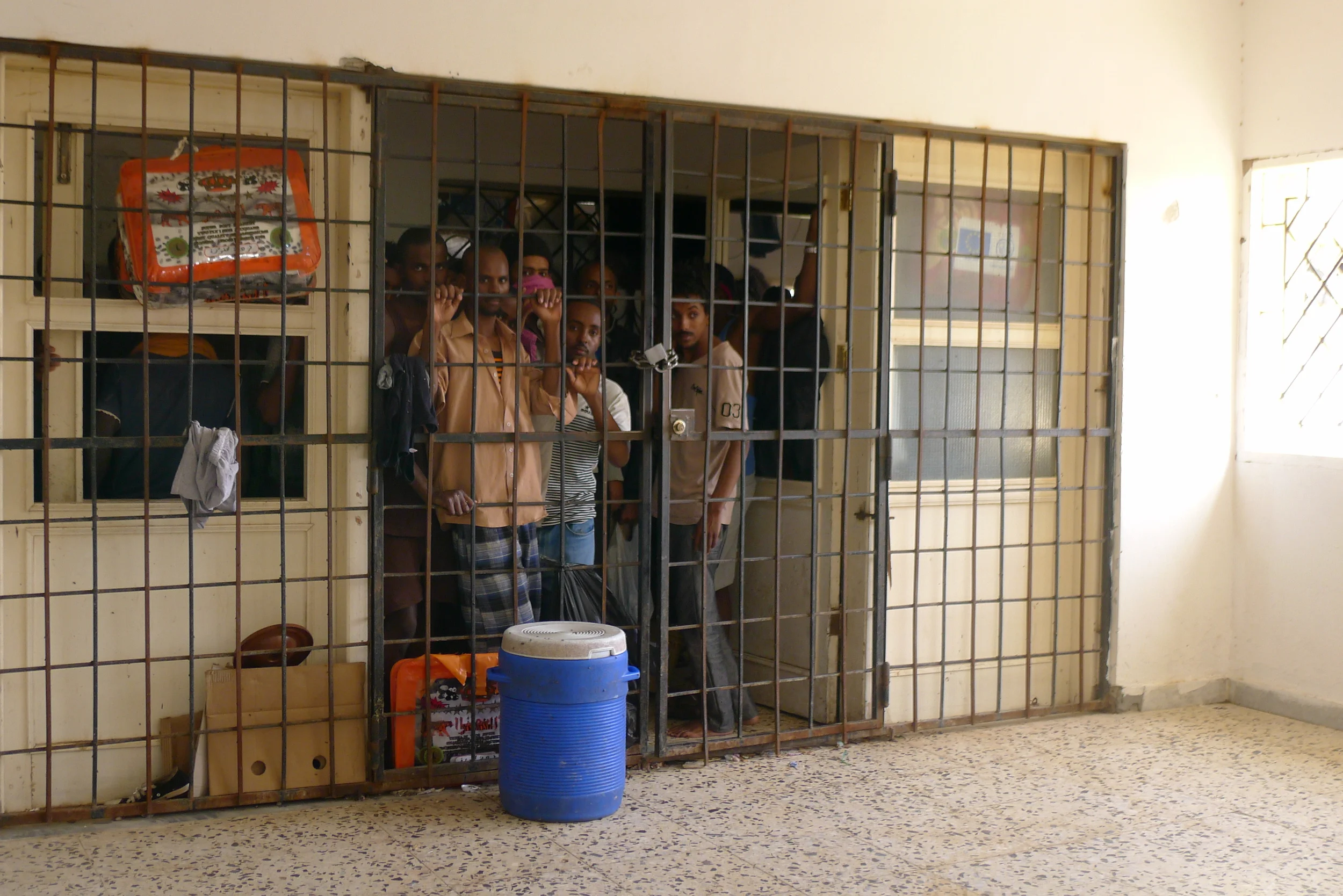 Migrants cluster behind the entrance to the first floor of the detention centre.