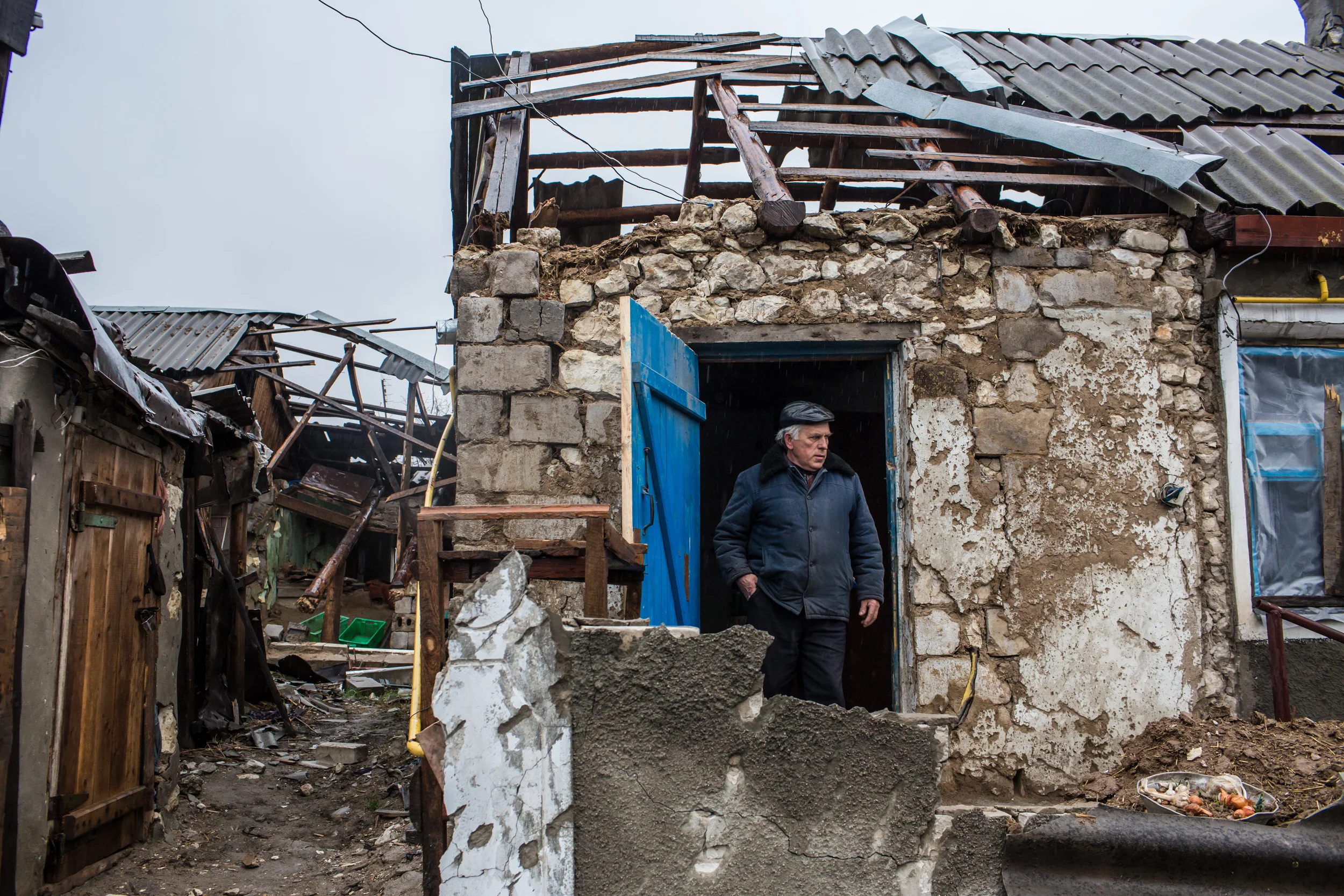 Ivan Kubarev, 61, shows the destroyed home of his elderly relatives in Triokhizbenka, who are now sheltering with him and his wife nearby. (Brendan Hoffman for Mercy Corps)