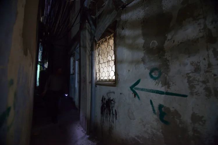 Dans une allée sombre, un homme éclaire son chemin à la lumière d’un porte-clés