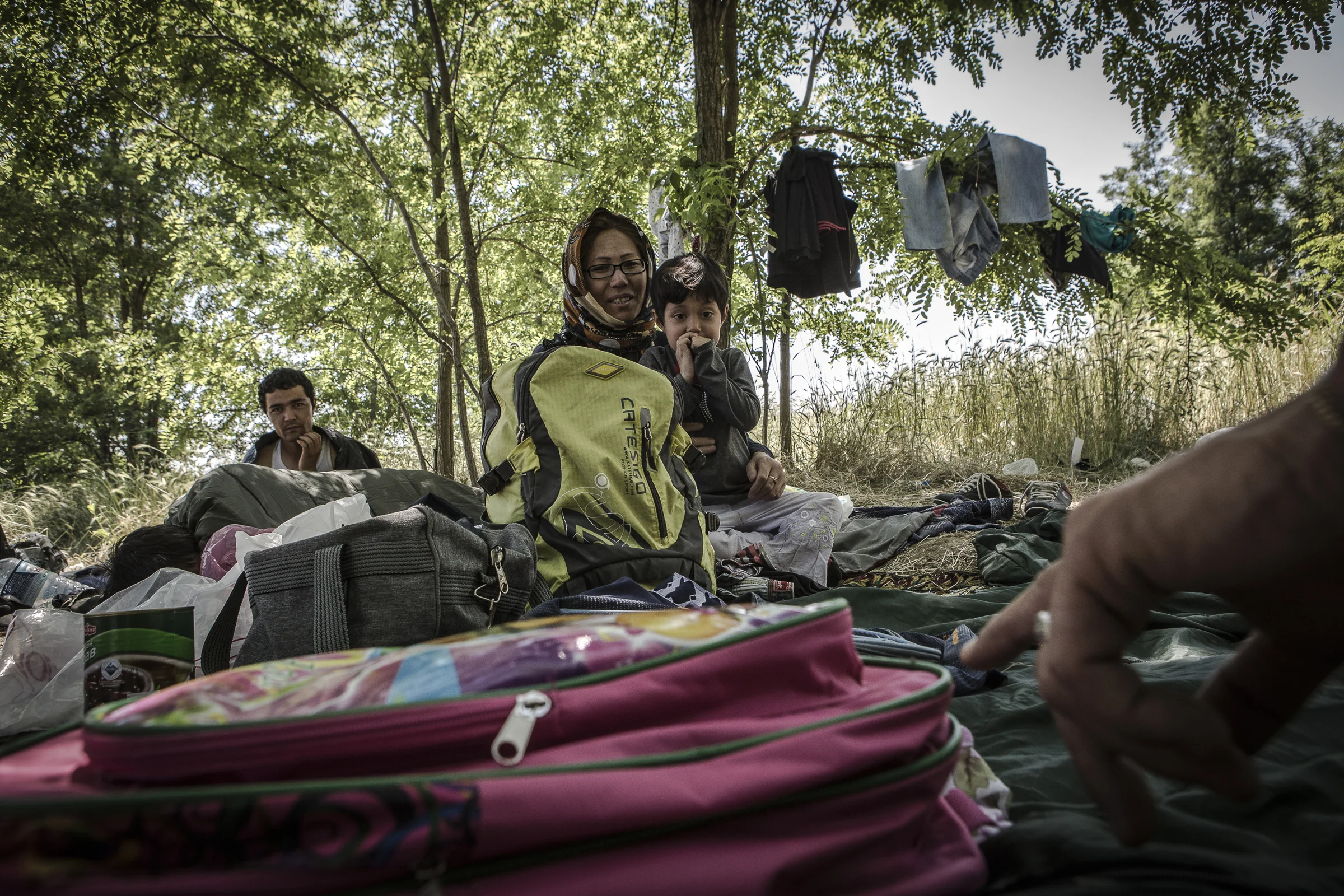 An Afghan woman and her daughter rest in the border area known as "the jungle" where a criminal gang has been extorting migrants. 