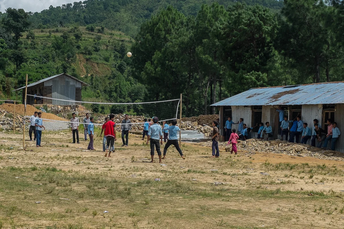 Students play volleyball during a break in classes near the temporary learning center set up on the grounds of their school on 10 August 2015 in Bhotsipa.
