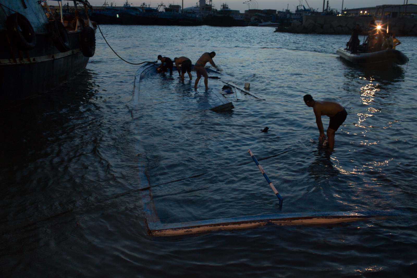 As the boat was towed into port, the grim task of removing trapped bodies began