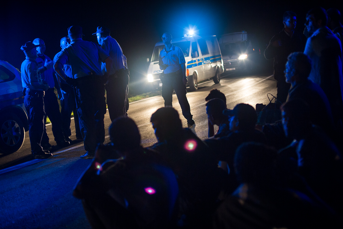 After tiring of waiting for a bus in Tovarnik, a group of refugees decide to continue on foot but are intercepted by the police who try to convince them to return to the village.