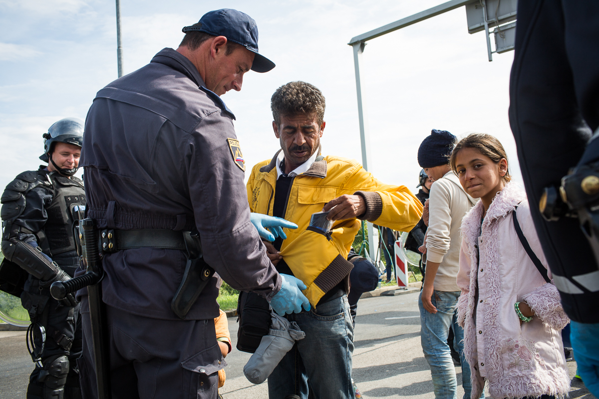Slovenian border police search refugees before they are allowed onto buses at Obrezje.