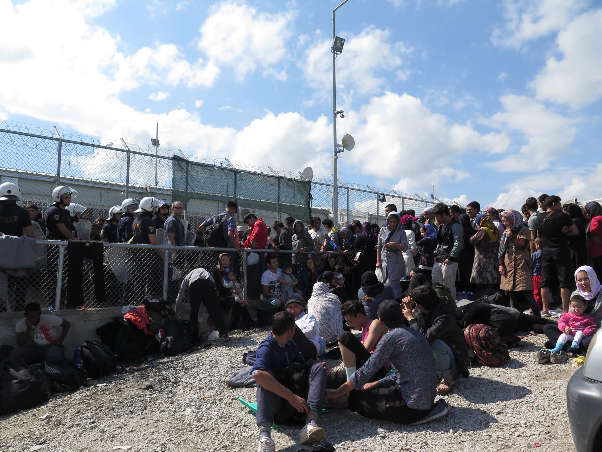 At Moria camp, Greek riot police push back non Syrian refugees from the barbed wire surrounding the registration centre. Here, people wait for hours in the hot sun before they can complete papers (Imogen Wall/IRIN)