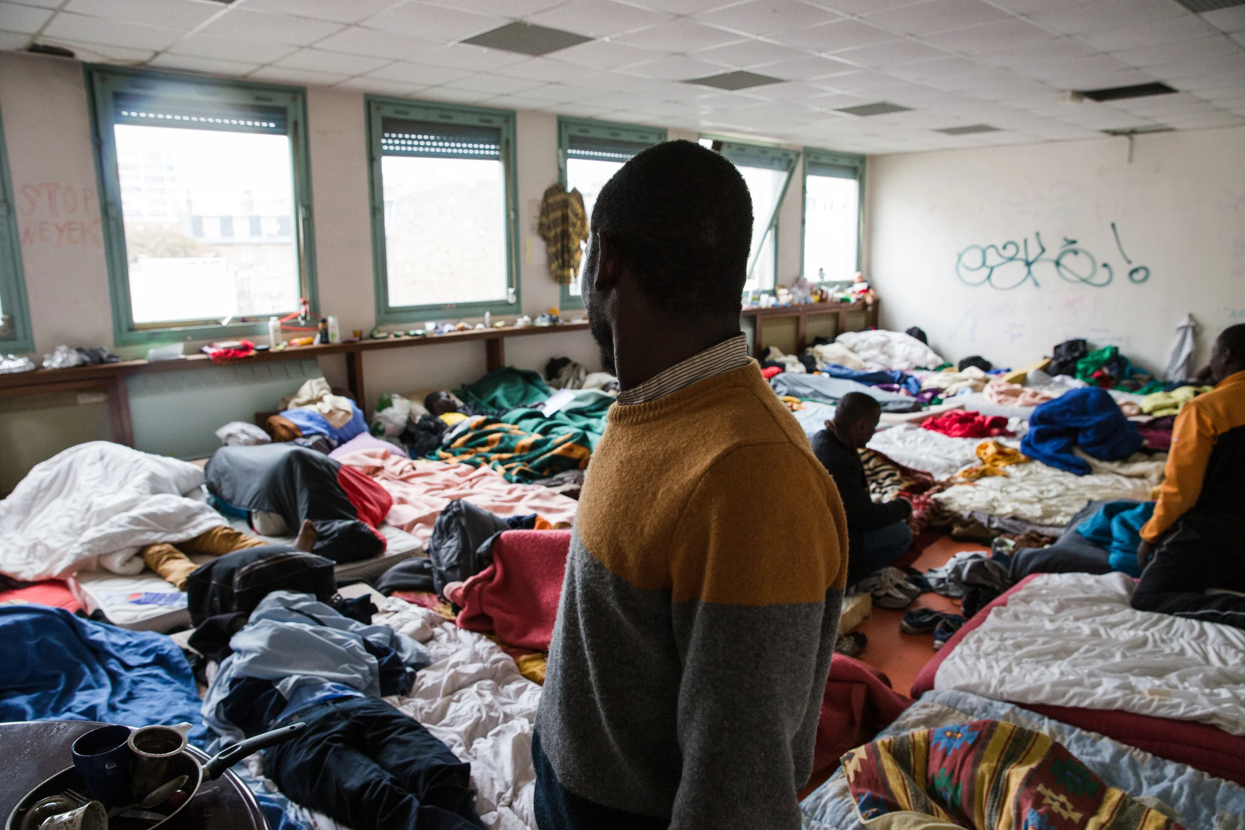 Des dizaines de personnes dorment dans cette salle de classe. Les réfugiés se regroupent par nationalité. Ceux-ci sont tous soudanais.