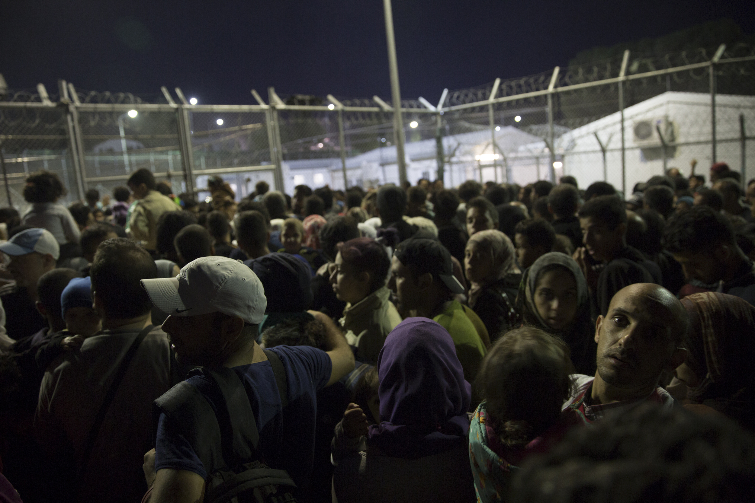   Refugees wait outside Moria, a former detention centre, to be fingerprinted and registered  