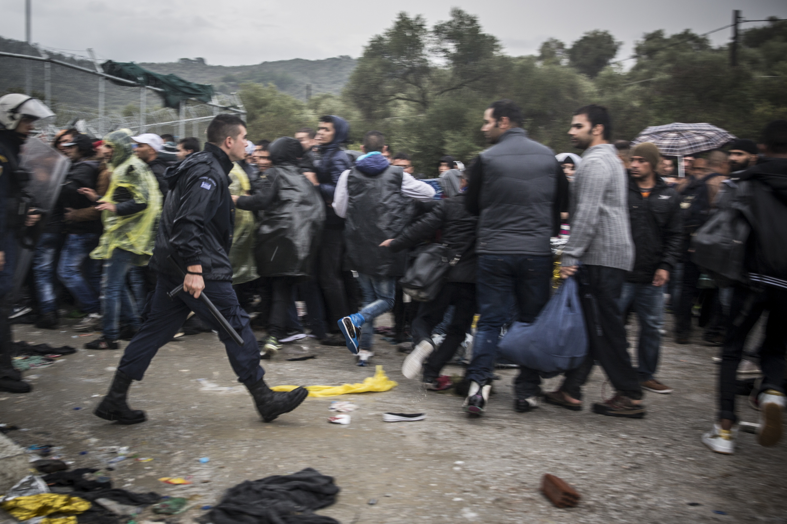   Riot police use aggressive tactics to control a crowd of refugees waiting to get into Moria  