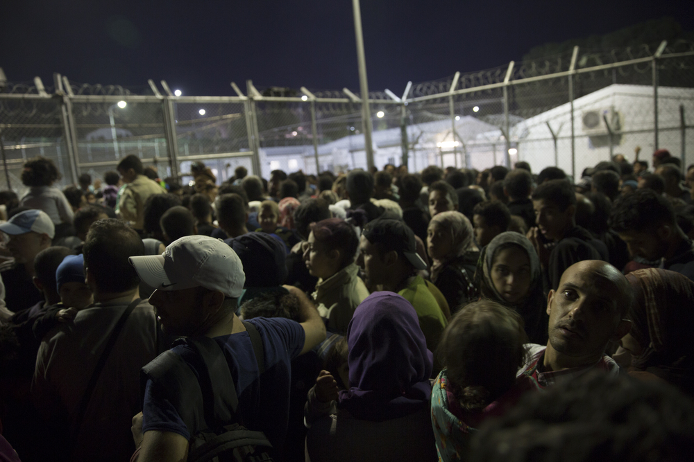   Des réfugiés attendent d’être enregistrés et de laisser leurs empreintes digitales, à l’extérieur du centre de détention de Moria  