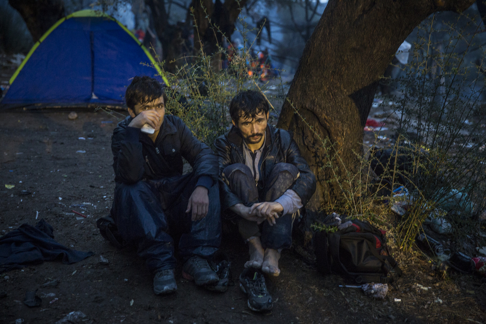  Deux réfugiés afghans campent sous la pluie, à l’extérieur de Moria  