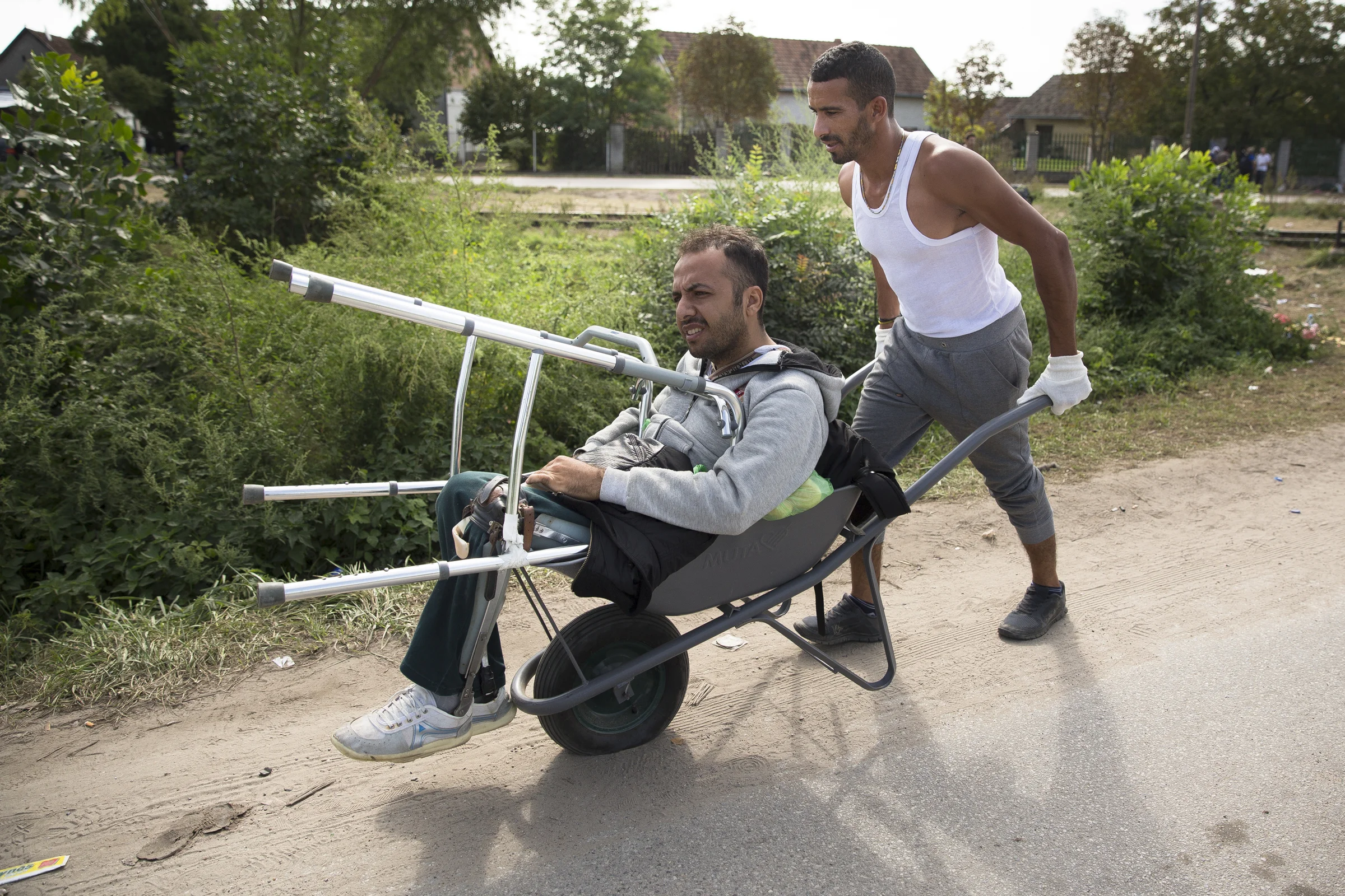 Massur Nasser pousse son ami, Gazi El Fadour, installé dans une brouette qui a un pneu crevé à Horgos, en Serbie. M. El Fadour a perdu ses jambes lors de l’attaque de l’université d’Alep par l’EI. Les deux hommes voyagent ensemble depuis leur rencontre en Turquie il y a quelques mois.