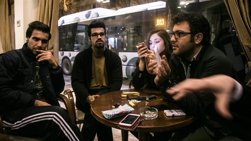 Aral Kakl (right), a Kurdish Iraqi journalist, his Syrian wife Shevin, his brother Rewan and some other refugees who have applied for the relocation programme, kill time in the cafeteria of their Athens hotel (Nicola Zolin/IRIN)