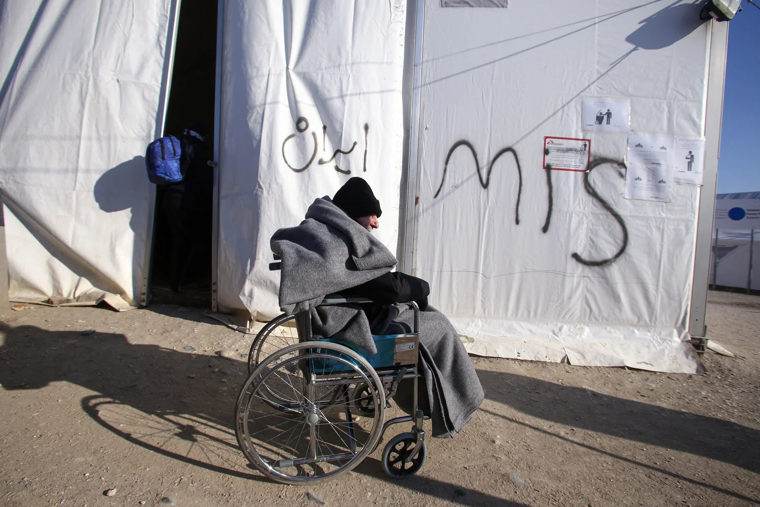 Un réfugié handicapé, emmitouflé contre le froid, devant l’une des tentes que MSF a été autorisé à monter devant une station-service devenue zone d’attente pour les réfugiés et migrants qui tentent d’atteindre la frontière