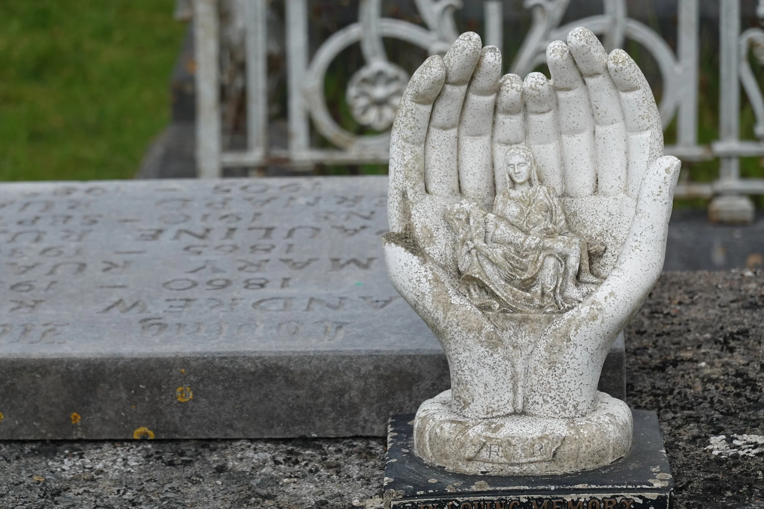 a sculpture at a cemetery of two hands holding two people