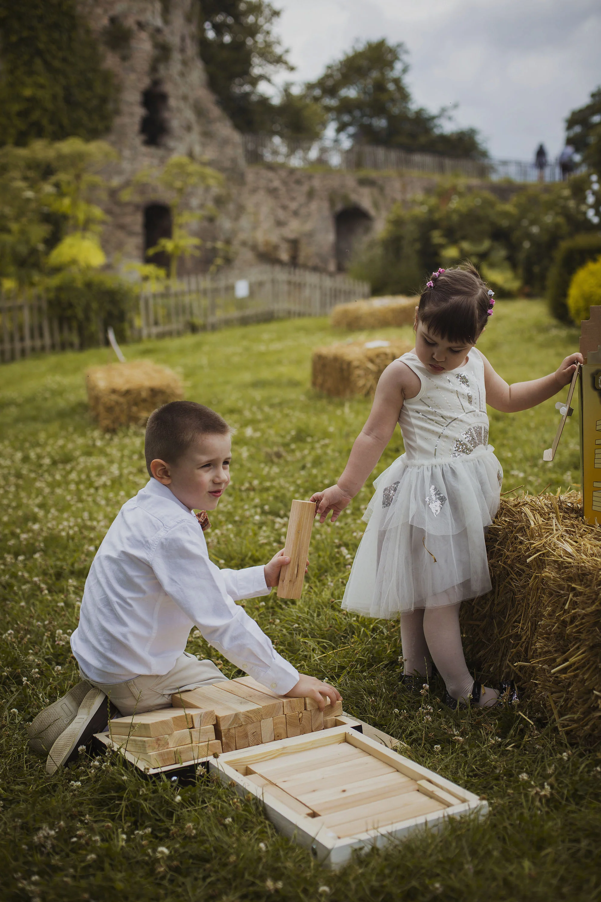 little girl handing giant jenga block to her older brother at wedding at usk castle