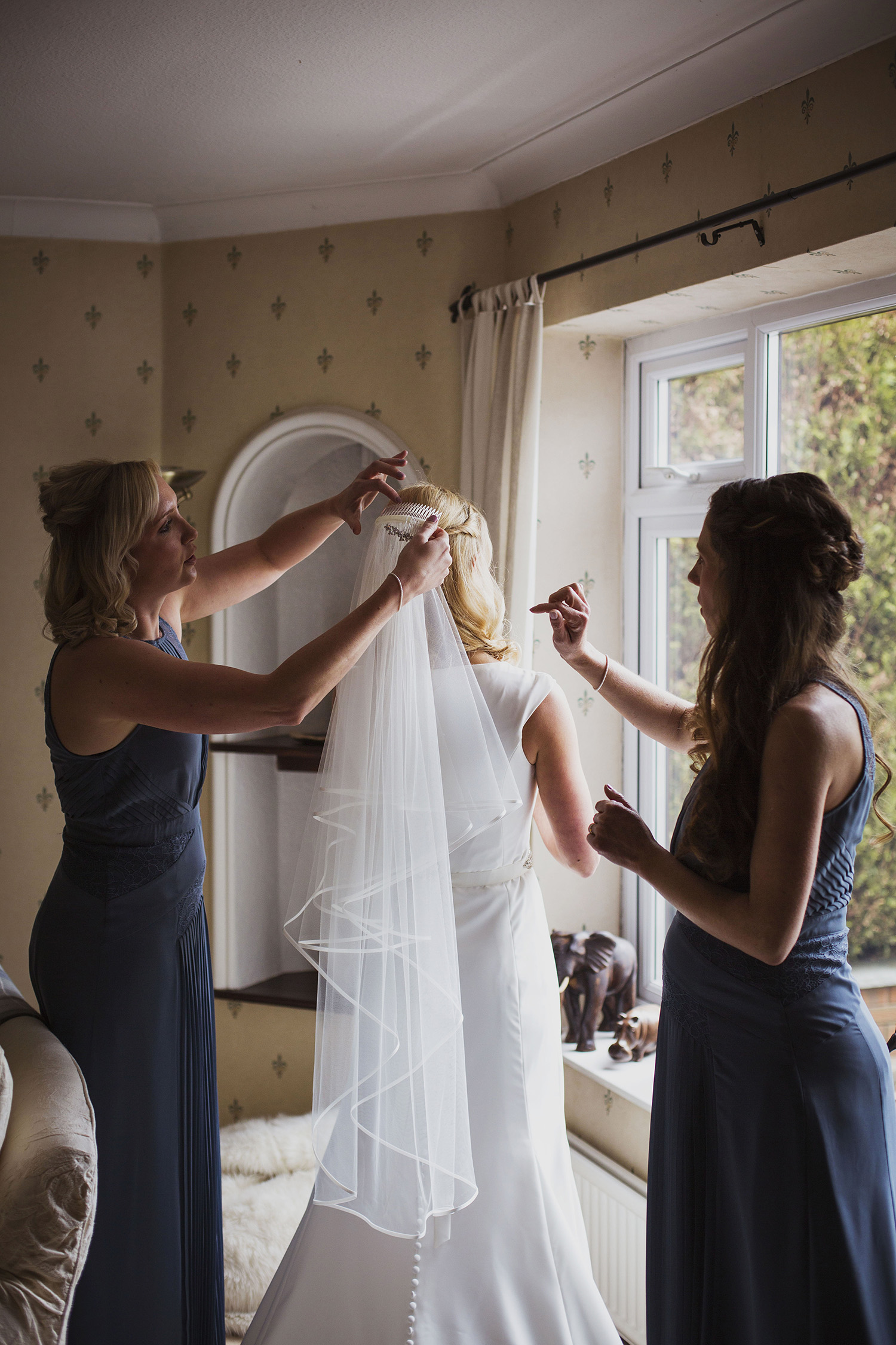 bride putting on veil at diy wedding in midlands