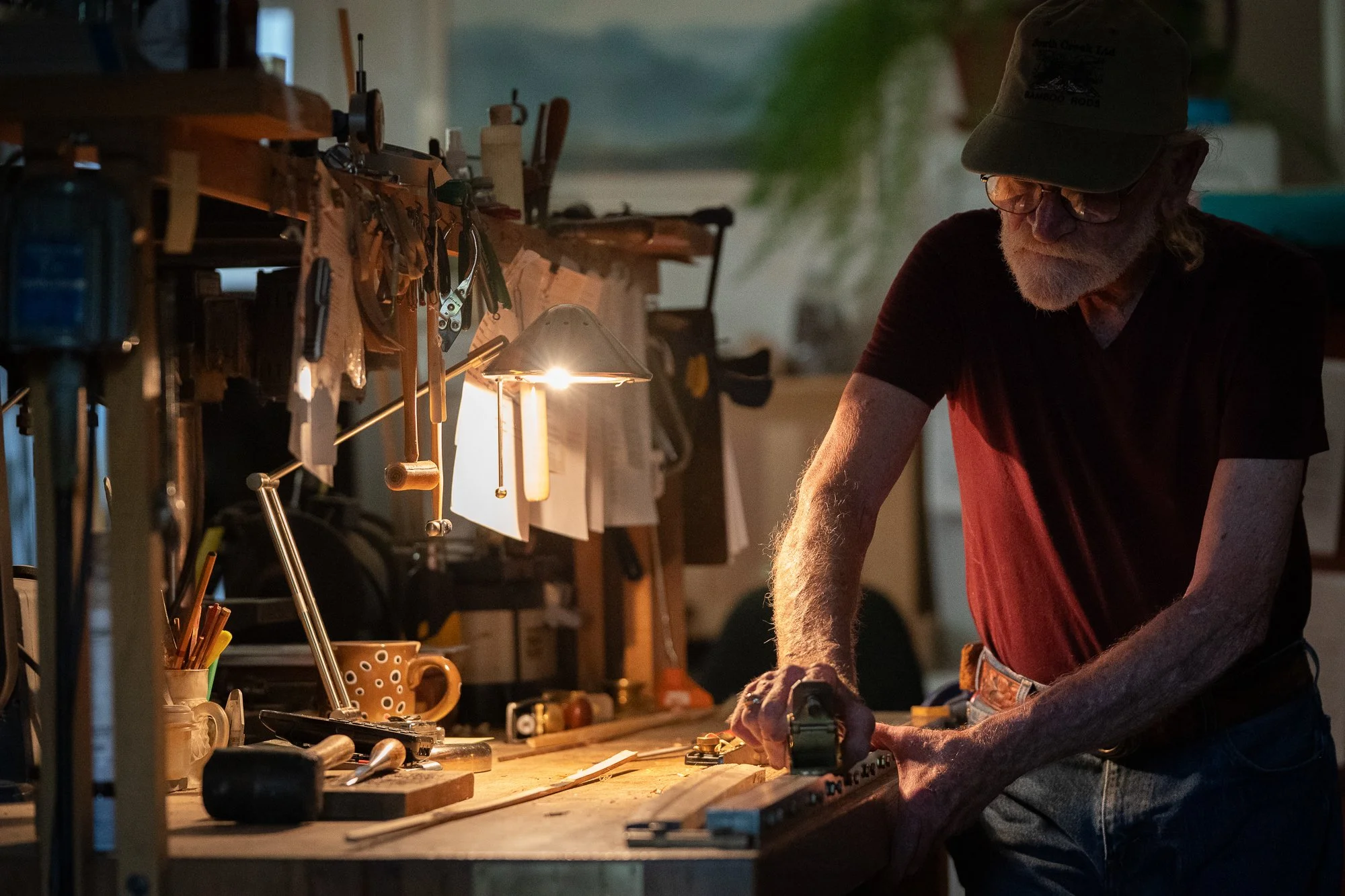 Mike Clark working a strip of bamboo at his bench during the fly rod building process.