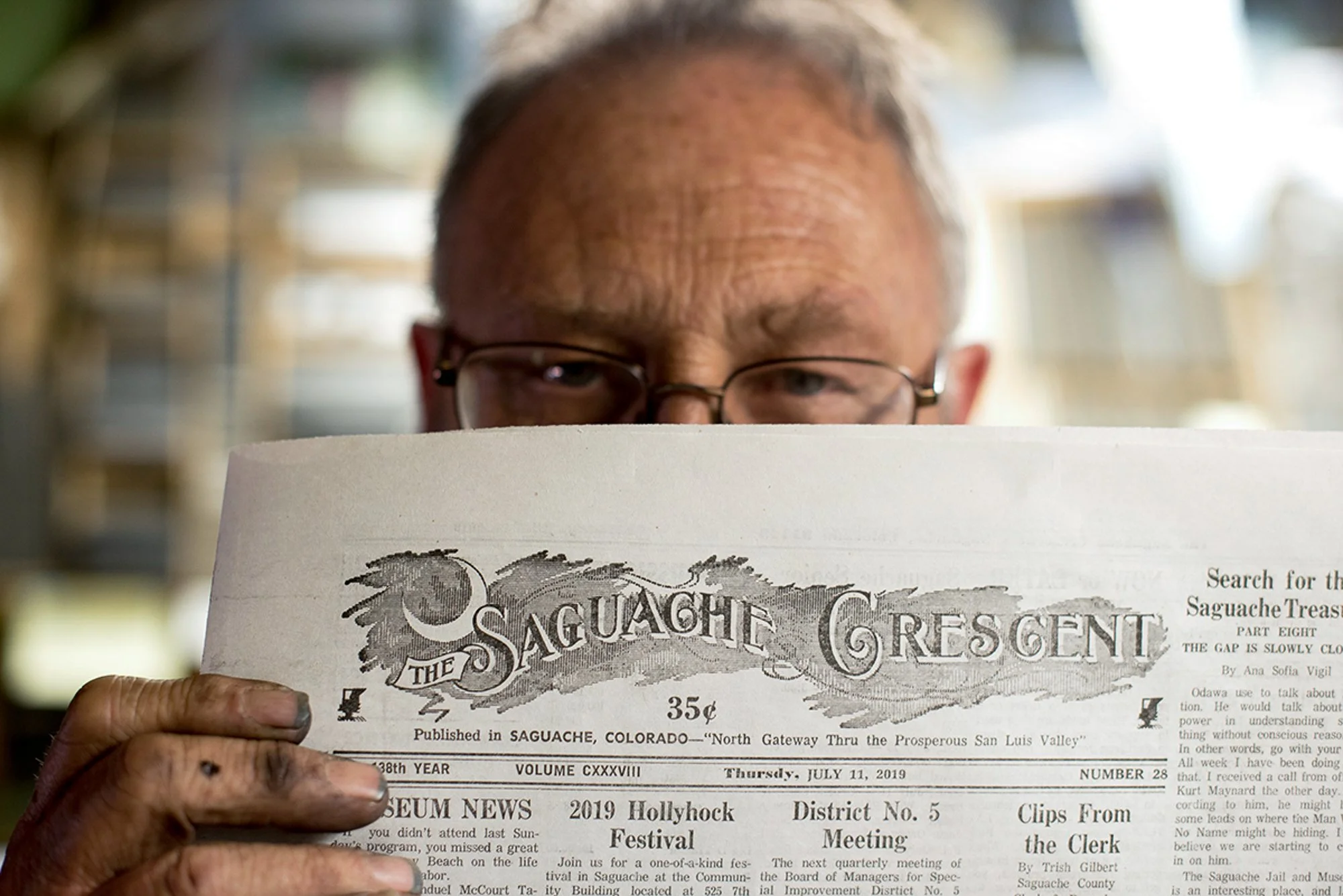 Dean Coombs holding a copy of the Saguache Crescent newspaper