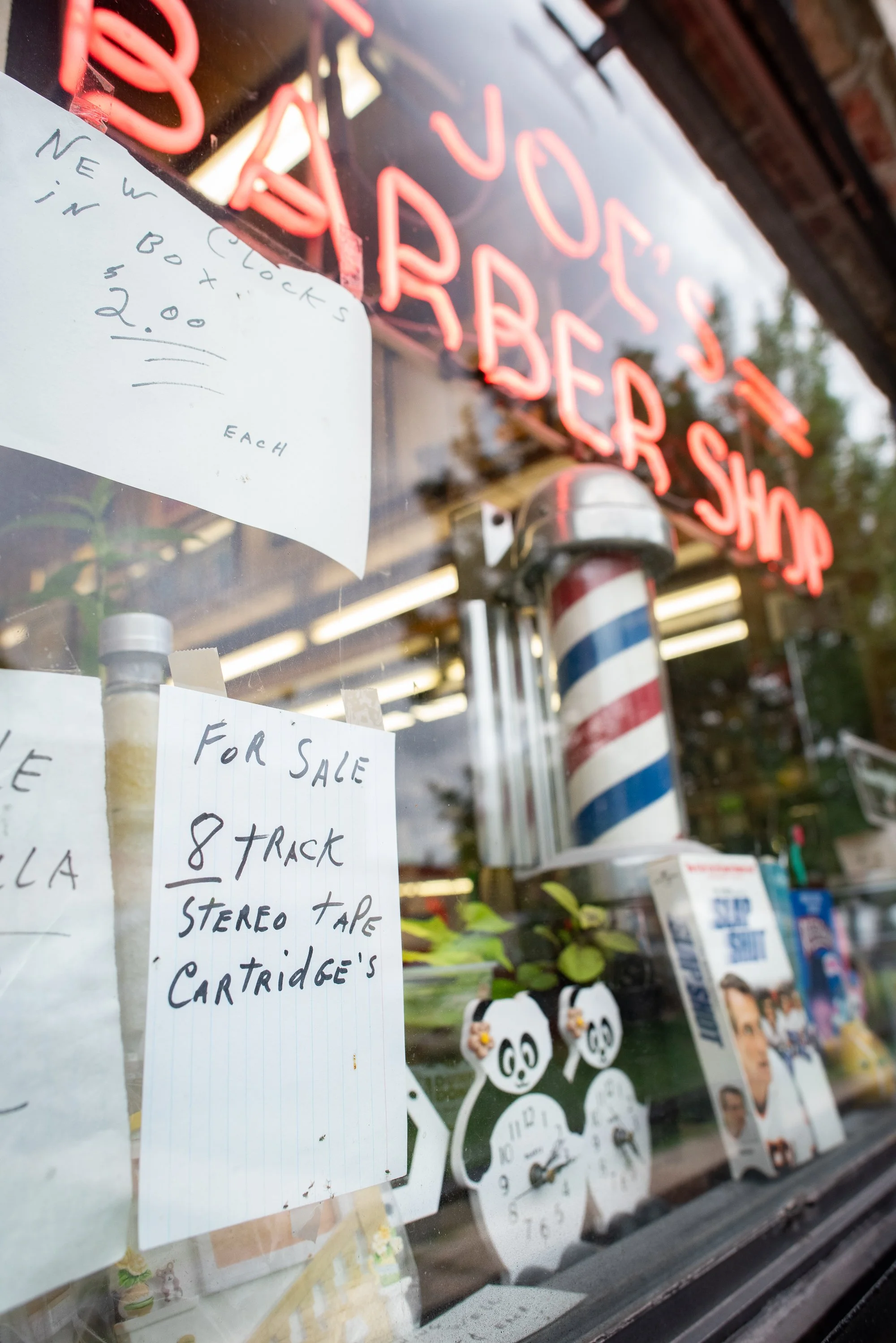 Barber pole and handwritten signs in the window of Joe’s Barbershop in Chicago