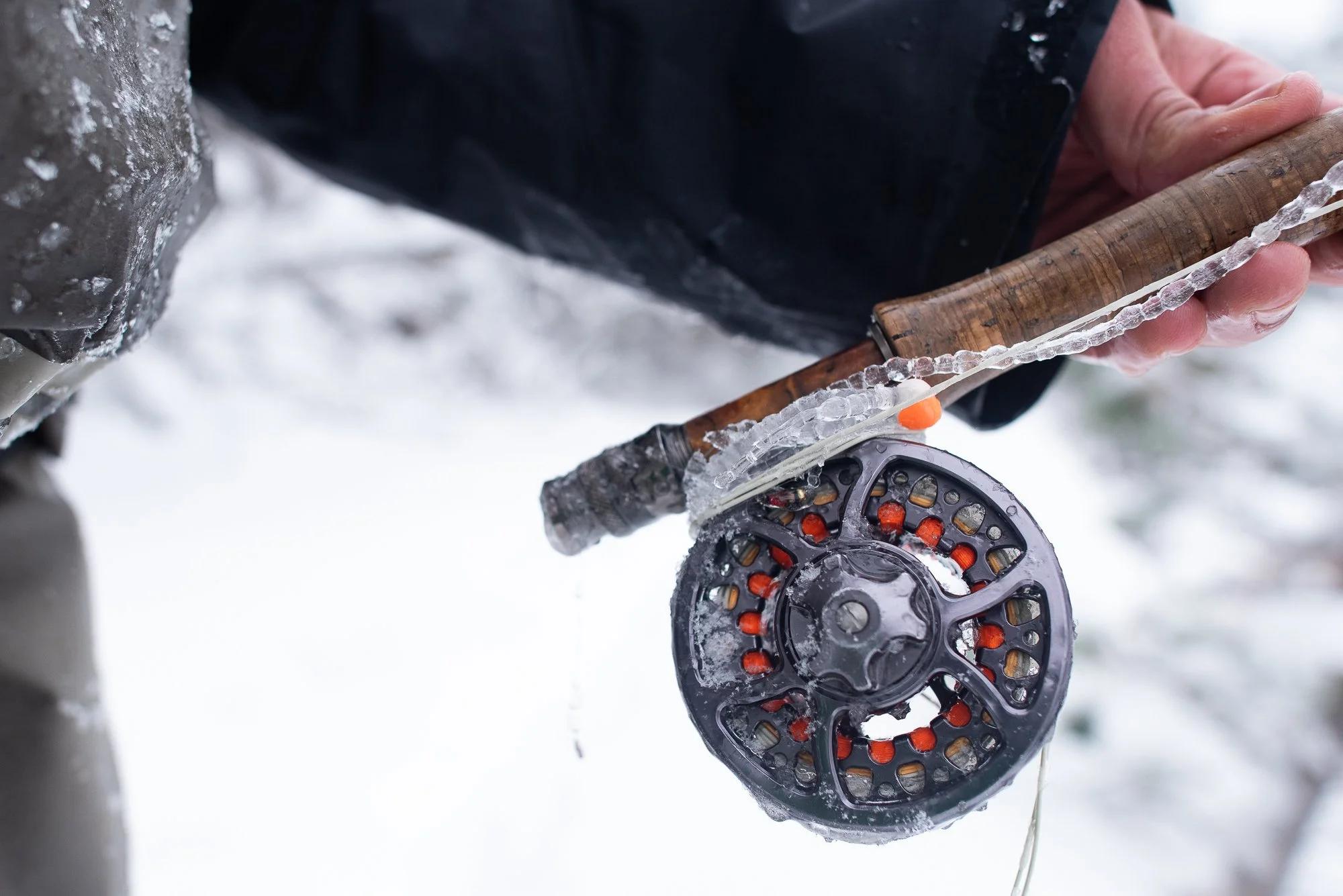 A close-up of a fly fishing rod and reel covered in ice during winter fishing on Clear Creek.