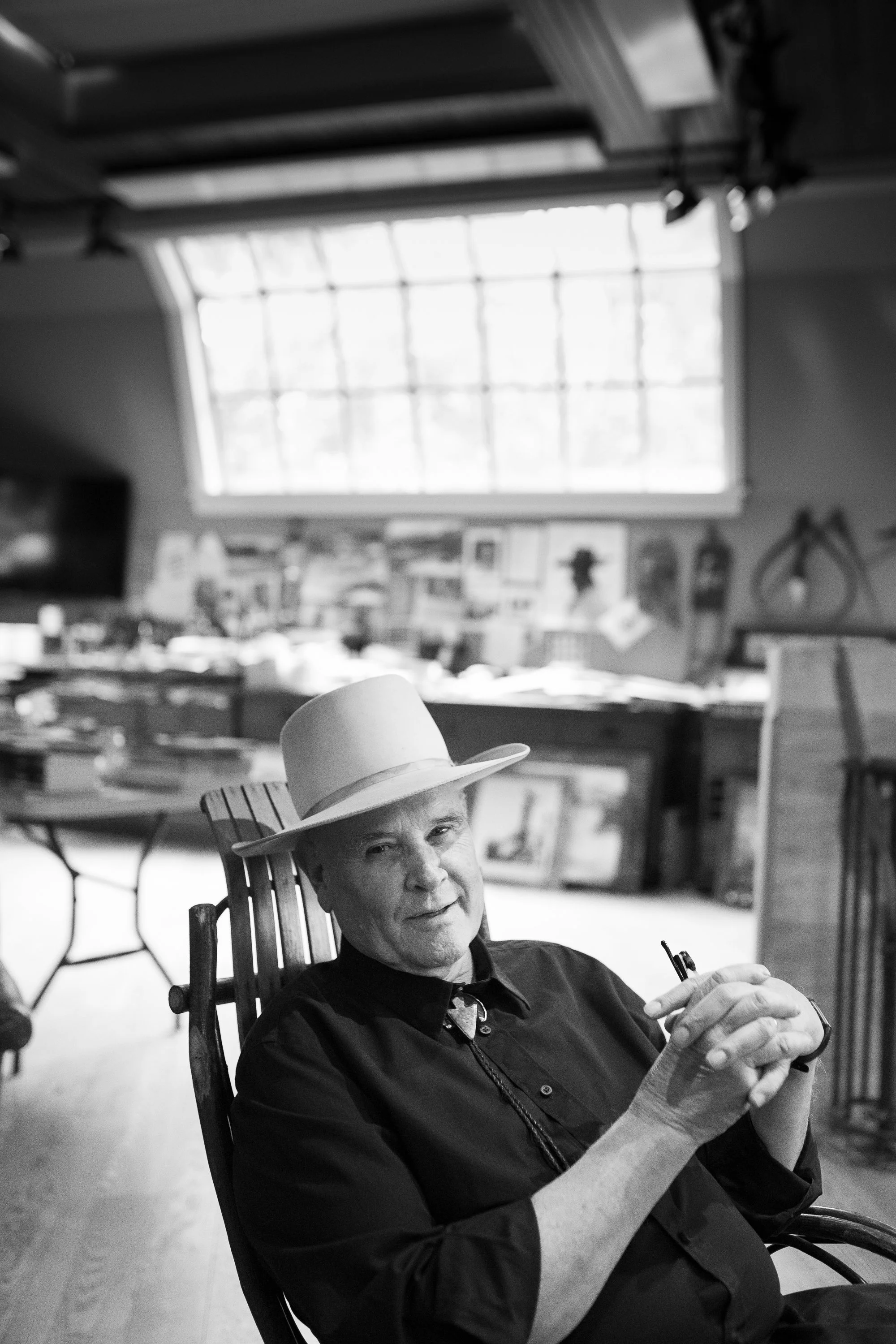 William Matthews seated in rocking chair inside his art studio under large window