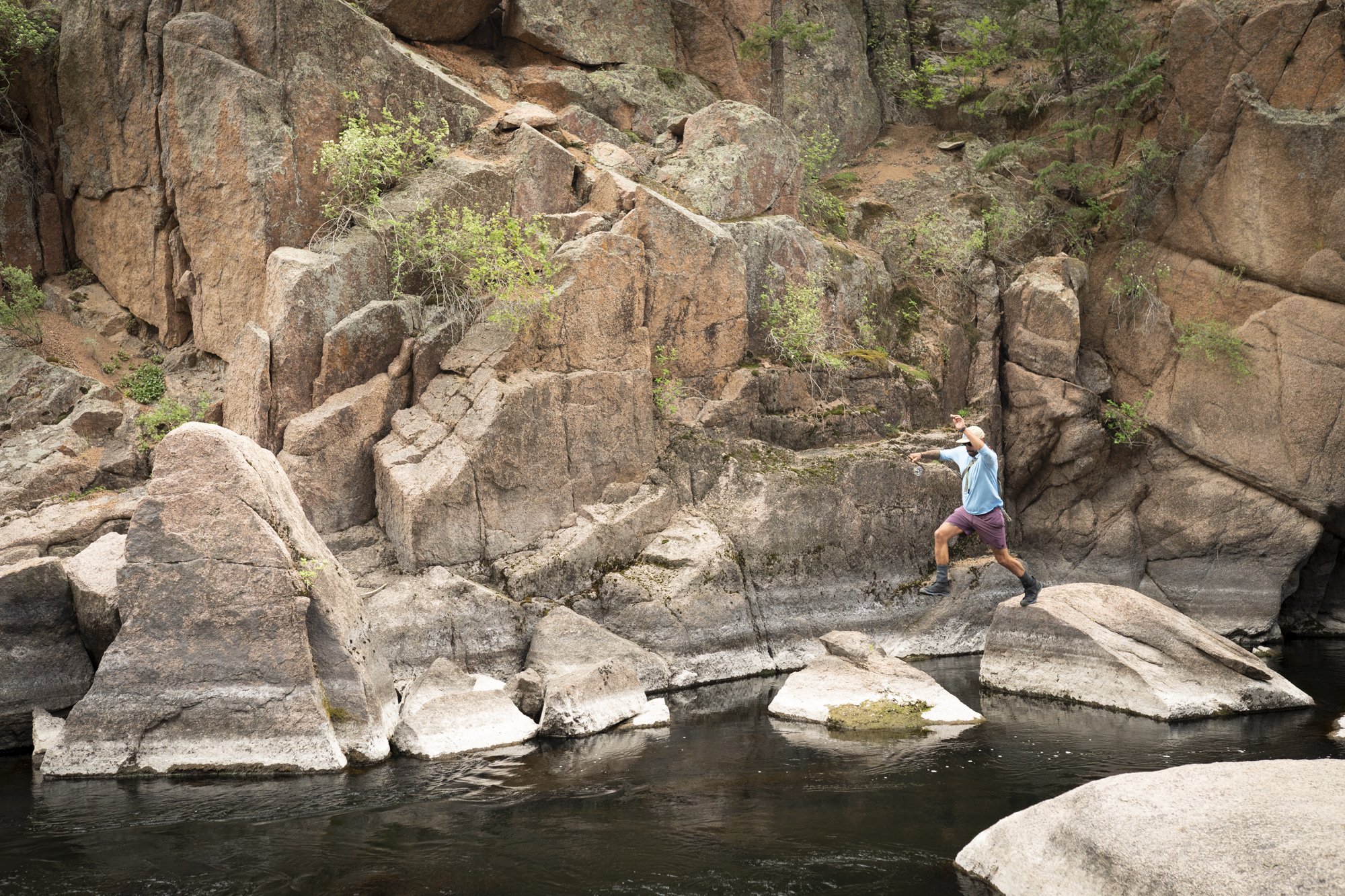 A fly fisherman jumps from boulder to boulder on the South Platte River in Cheesman Canyon, Colorado