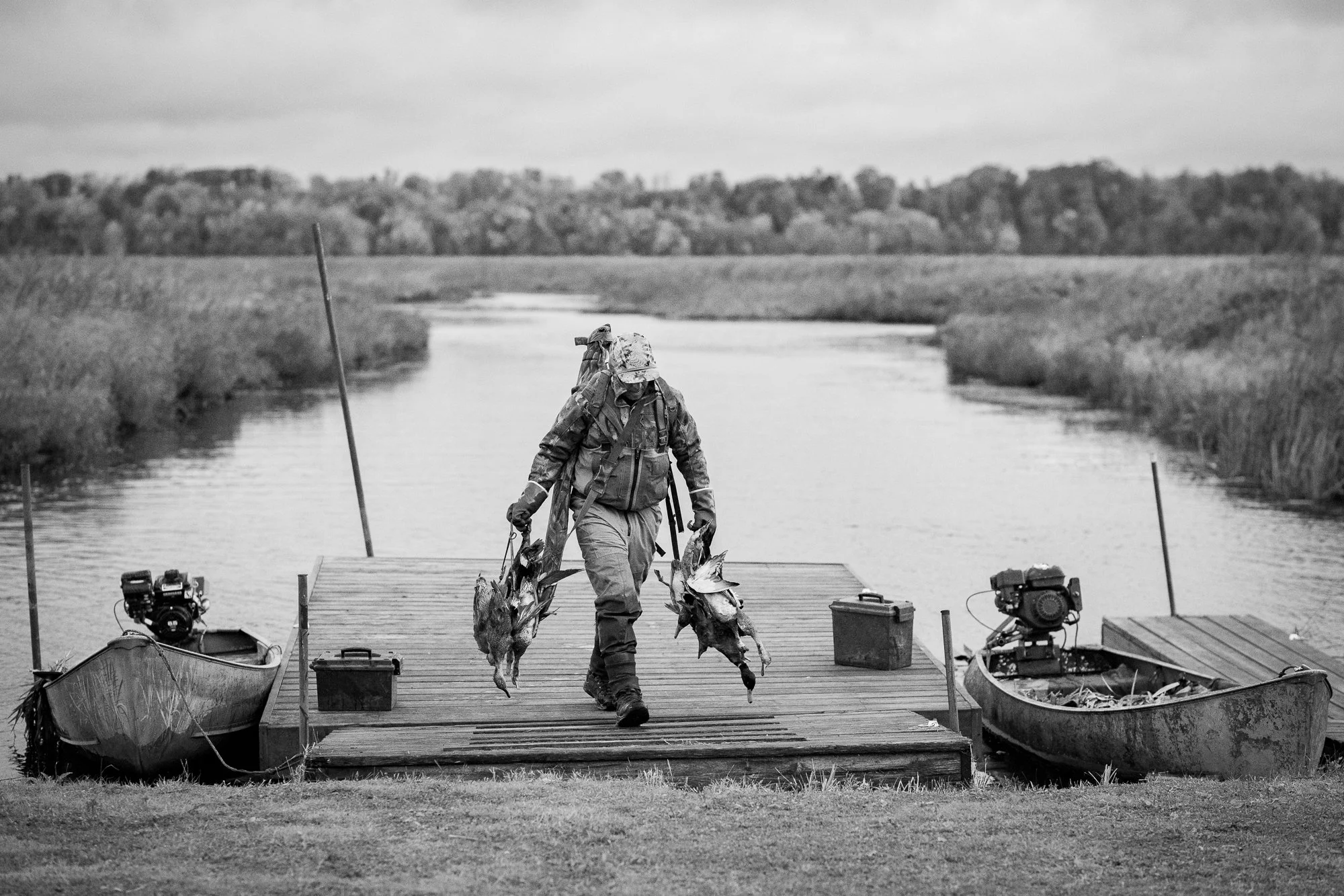 A duck hunter carries harvested waterfowl from the dock after a hunt in Ontario