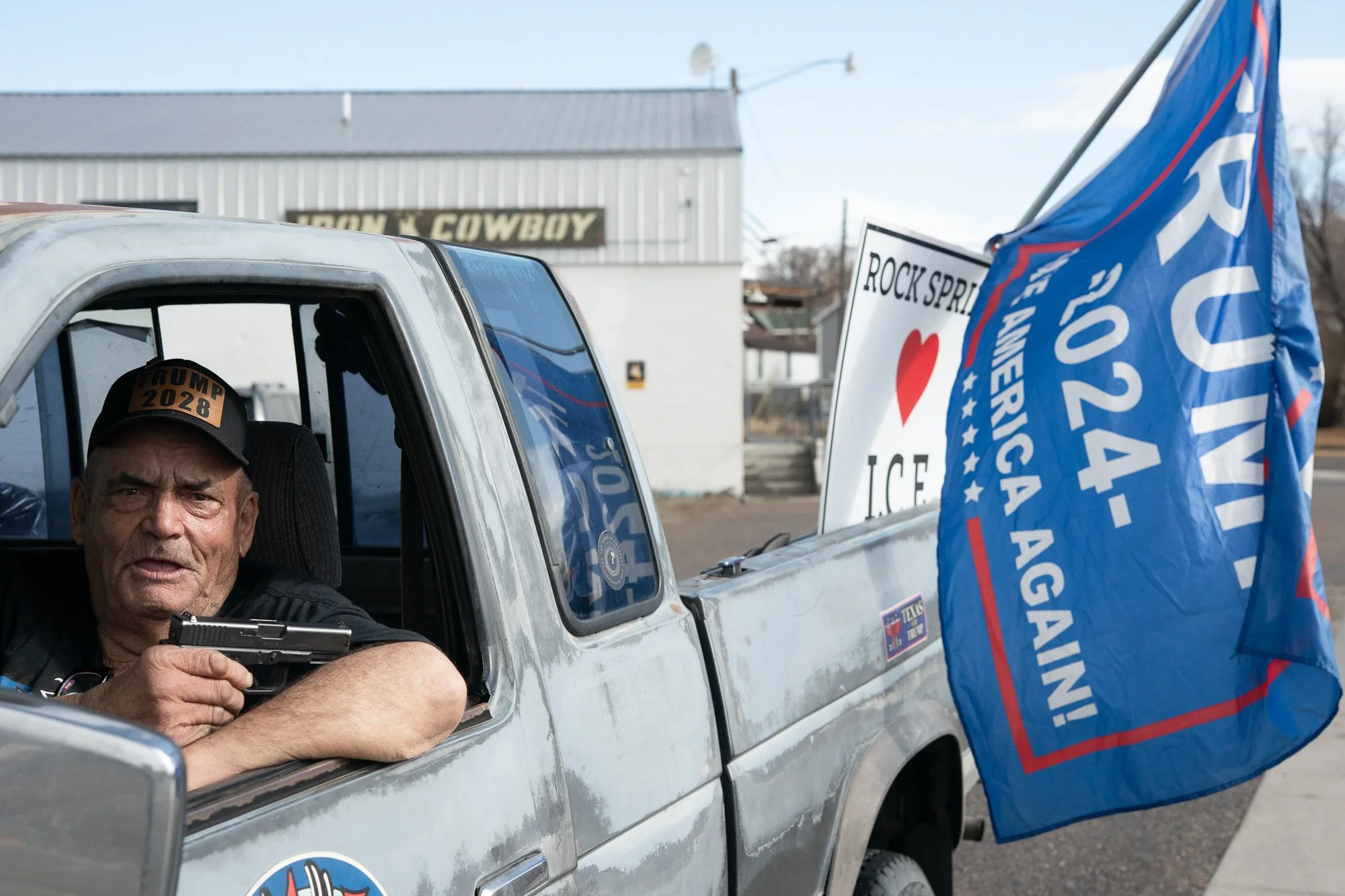 Man sitting in pickup truck with political flags along roadside in Rock Springs Wyoming