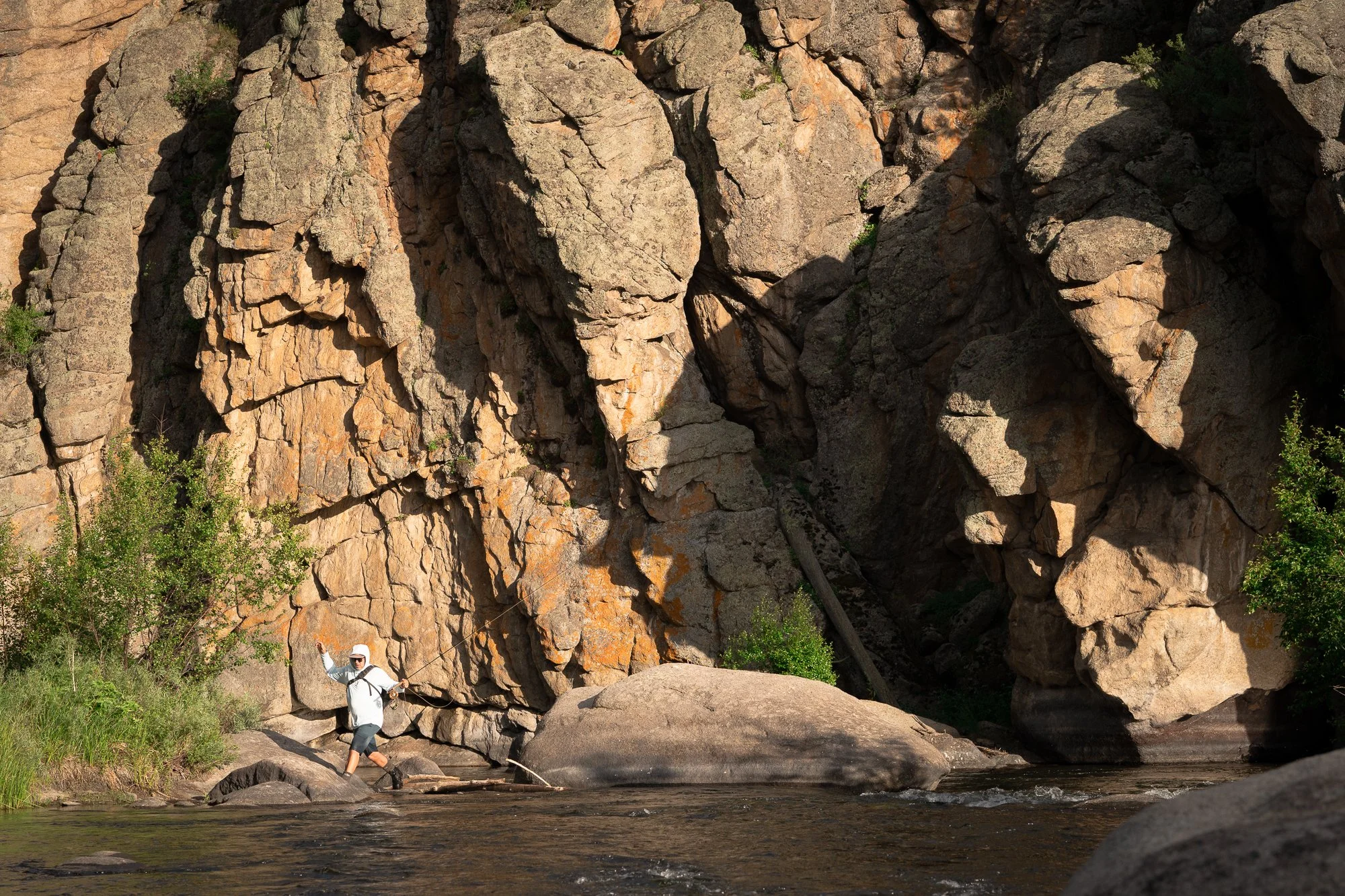A fly fisherman hopping from boulder to boulder in 11 Mile Canyon, Colorado