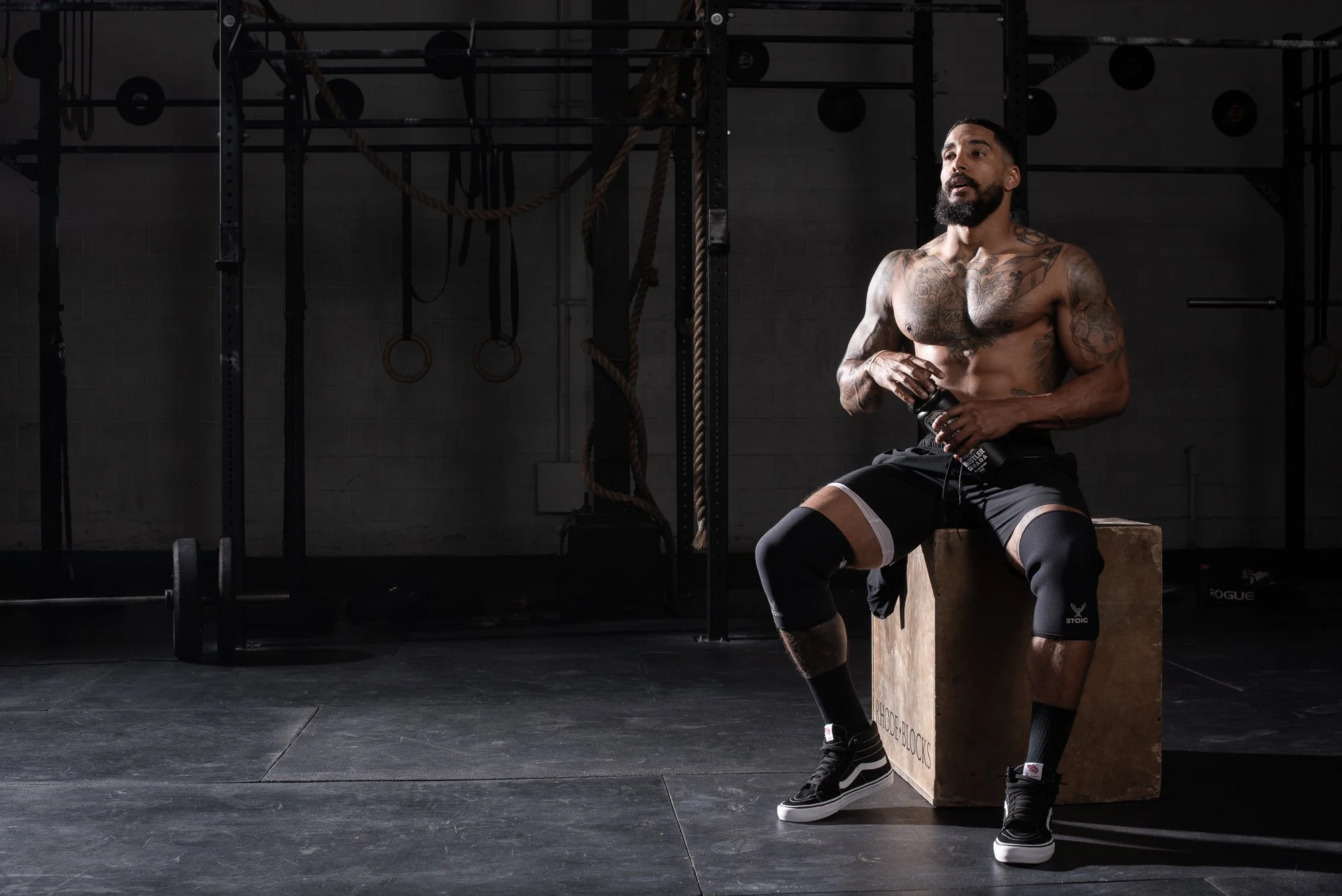 Athlete sits on a wooden box drinking water during a workout in a Colorado gym
