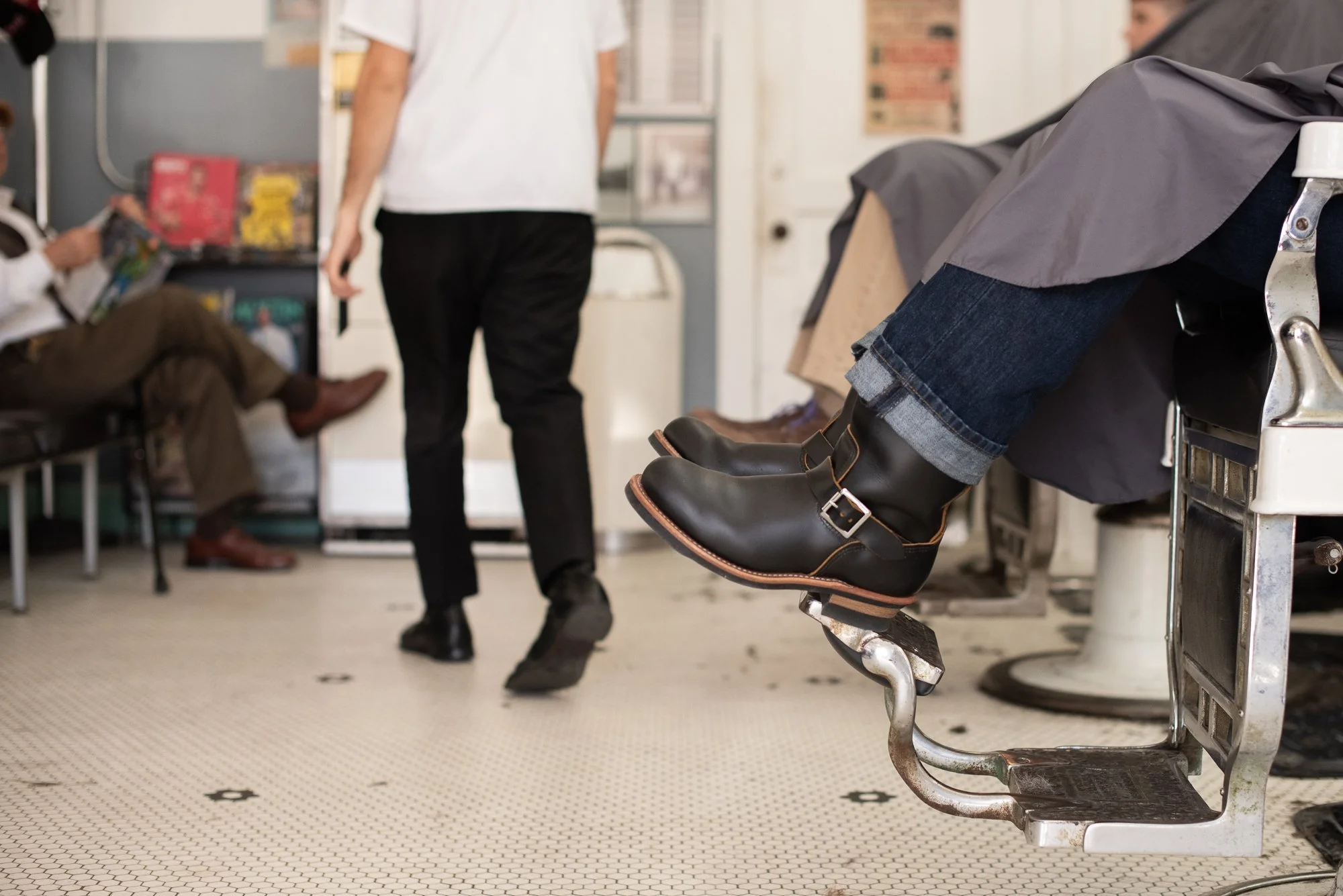 Black boots rest on the footrest of a barber chair inside Avenue Barbershop