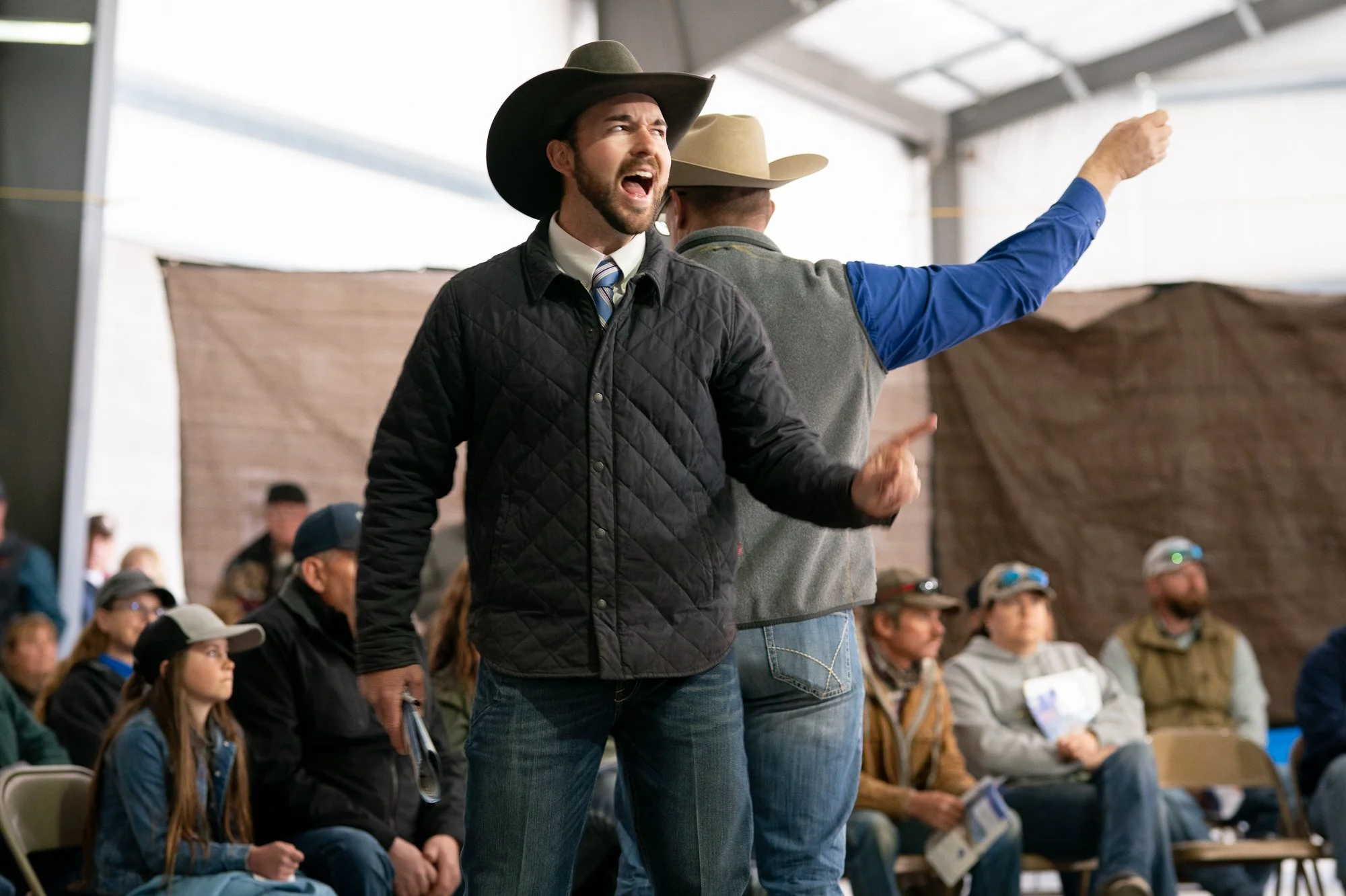 Auctioneer in a cowboy hat calling bids in front of ranchers at a Nevada bull sale