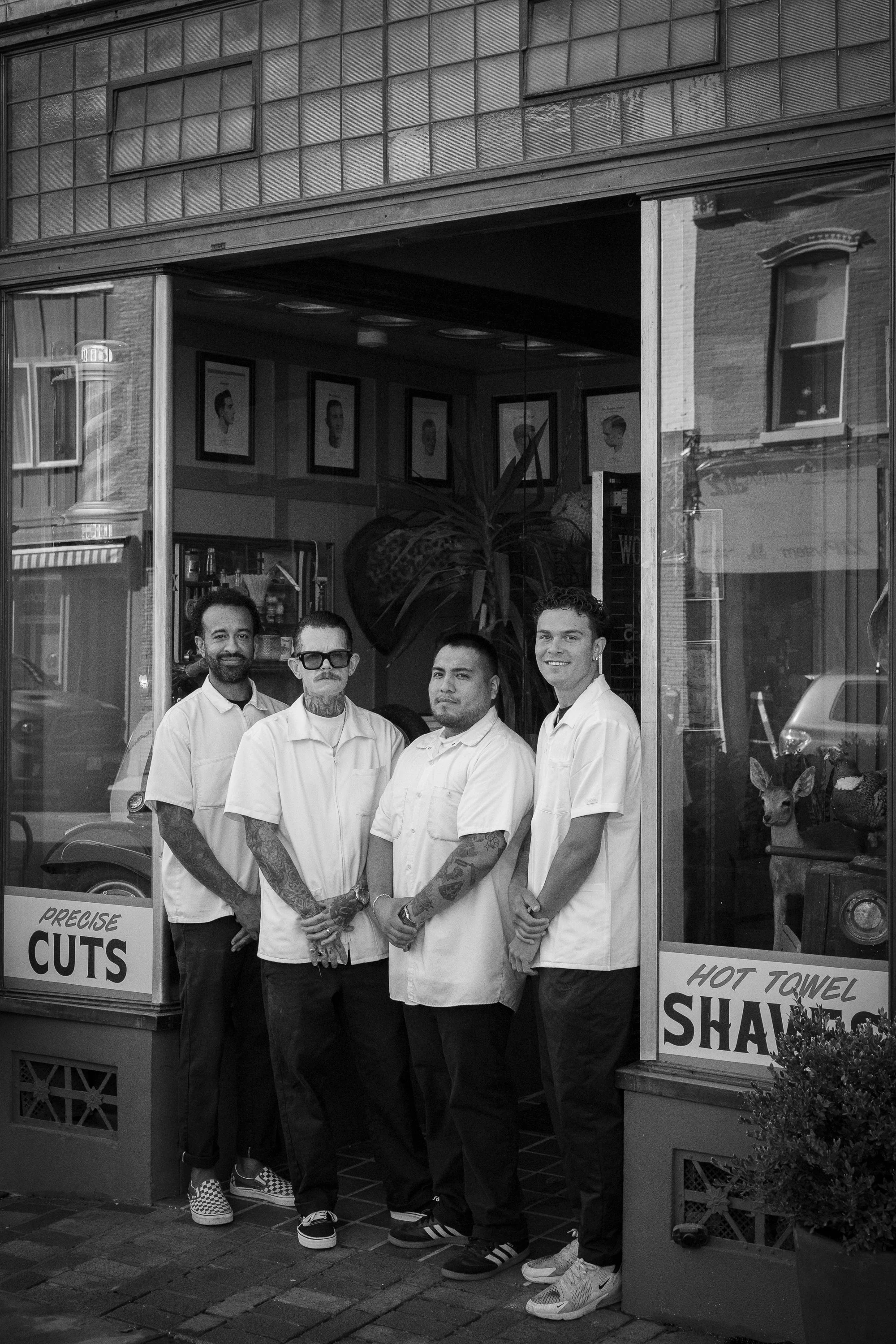 Four barbers standing together outside Pugsly's barbershop in matching white work shirts.Four barbers standing together outside Pugsly's barbershop in matching white work shirts.