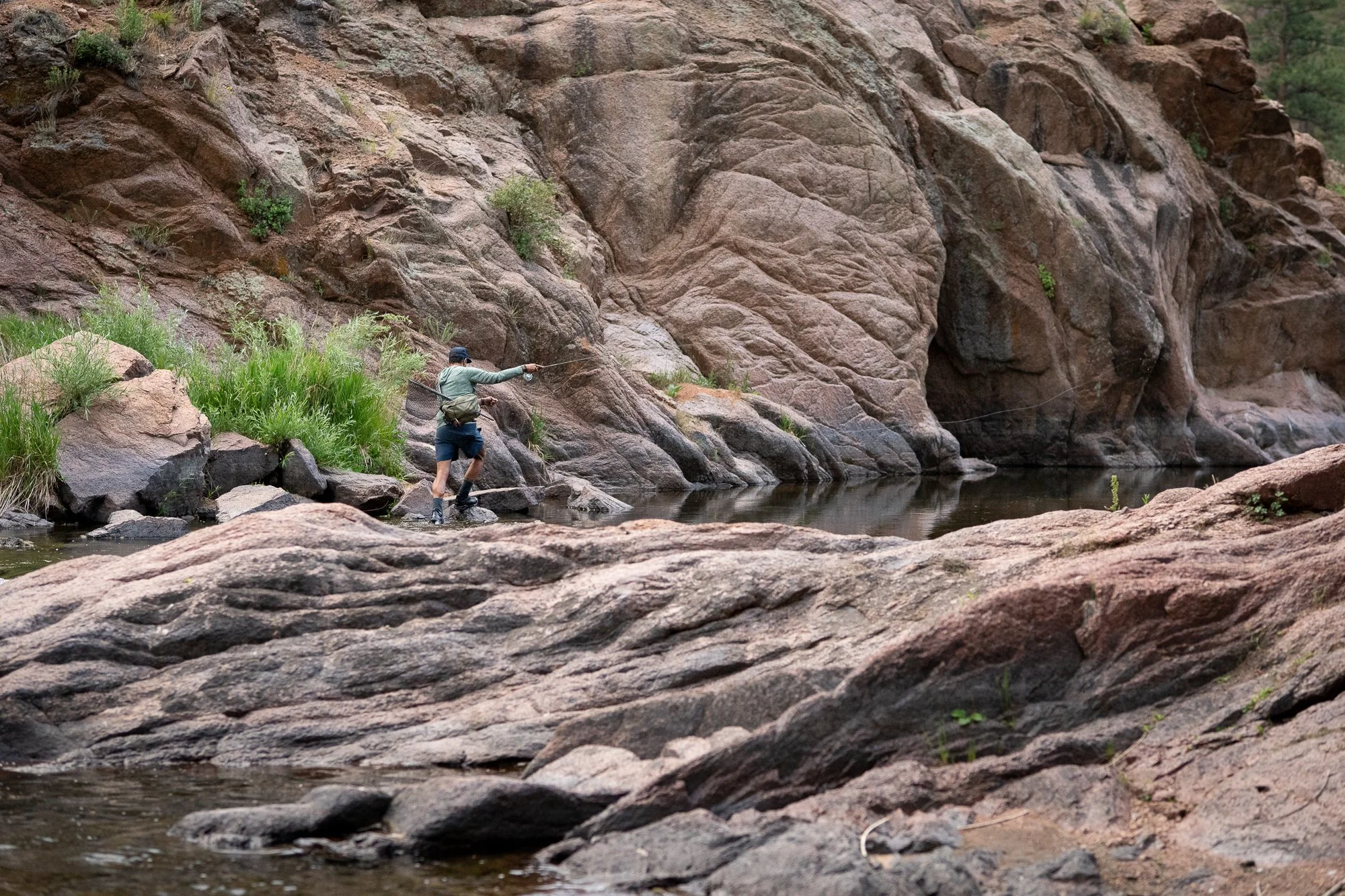 Angler casting beside canyon rock walls while fly fishing in Deckers Canyon