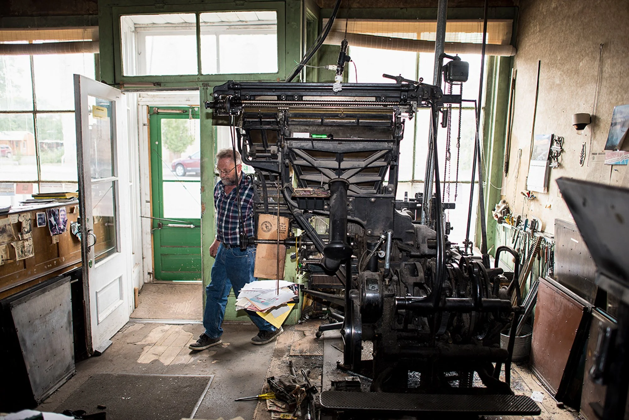Dean Coombs standing beside the printing press inside the Saguache Crescent